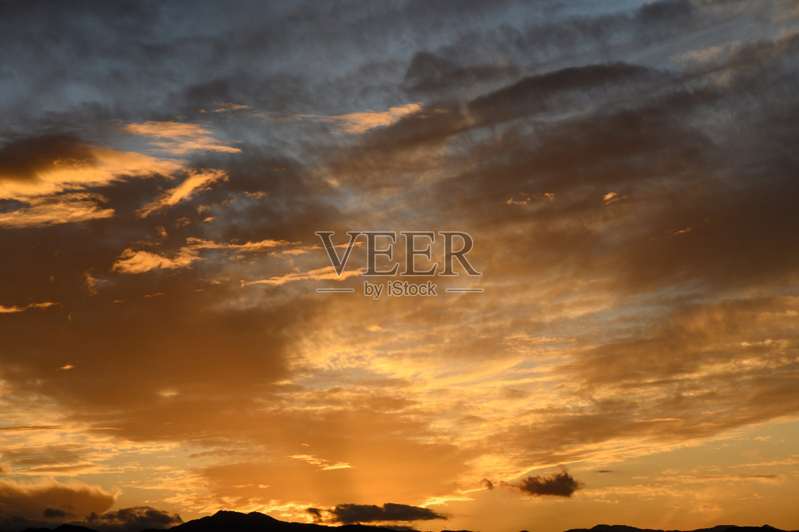 壮丽的日落将金色光辉洒在宁静的地平线上,云彩绚丽多彩。照片摄影图片