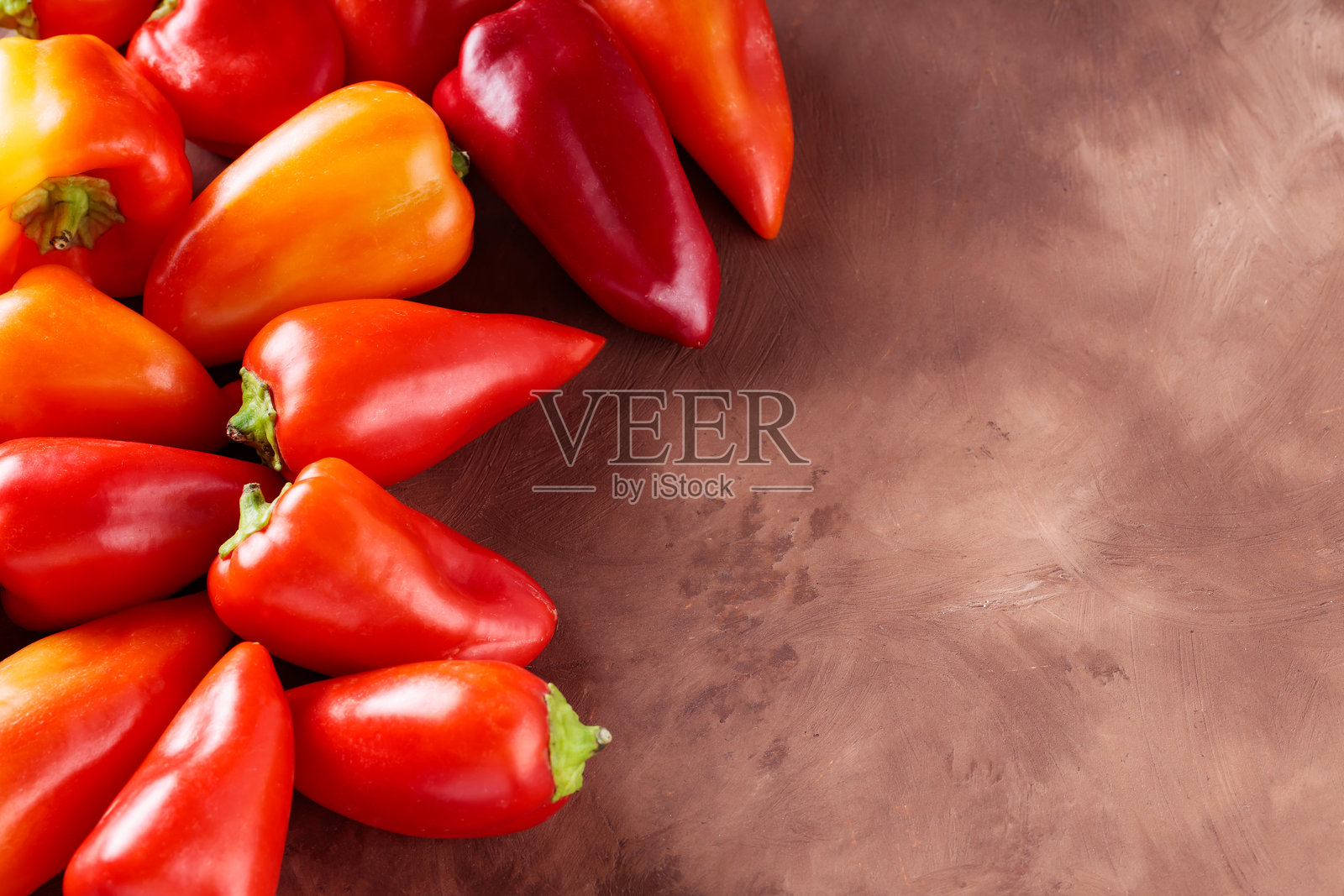 五彩缤纷的甜椒摆放在棕色陶土表面,适合新鲜素食烹饪,留有空白空间照片摄影图片