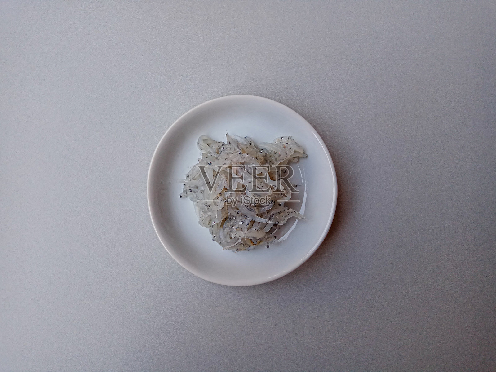 白bait或小鳀鱼或印尼的teri nasi。放在小白盘上,灰色背景。照片摄影图片