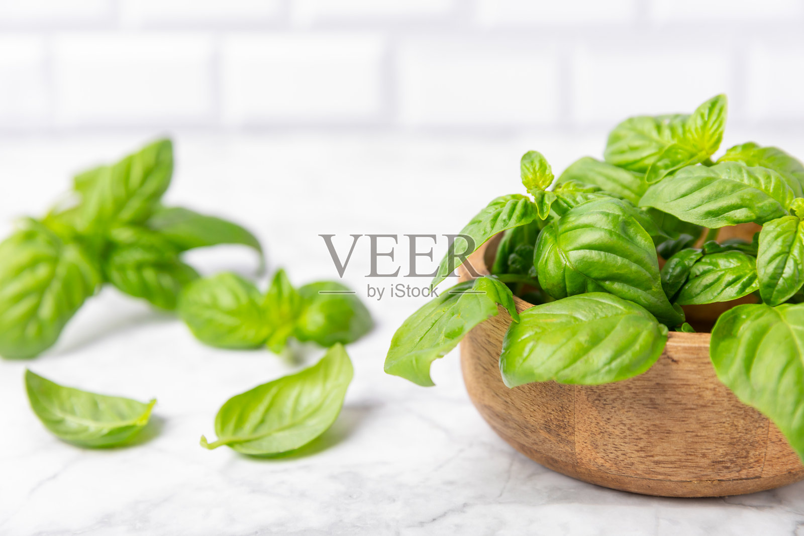 绿色罗勒叶子在有纹理的木质背景上。厨房香草,香料。新鲜绿色有机罗勒。素食。沙拉用的绿叶。留白处。照片摄影图片