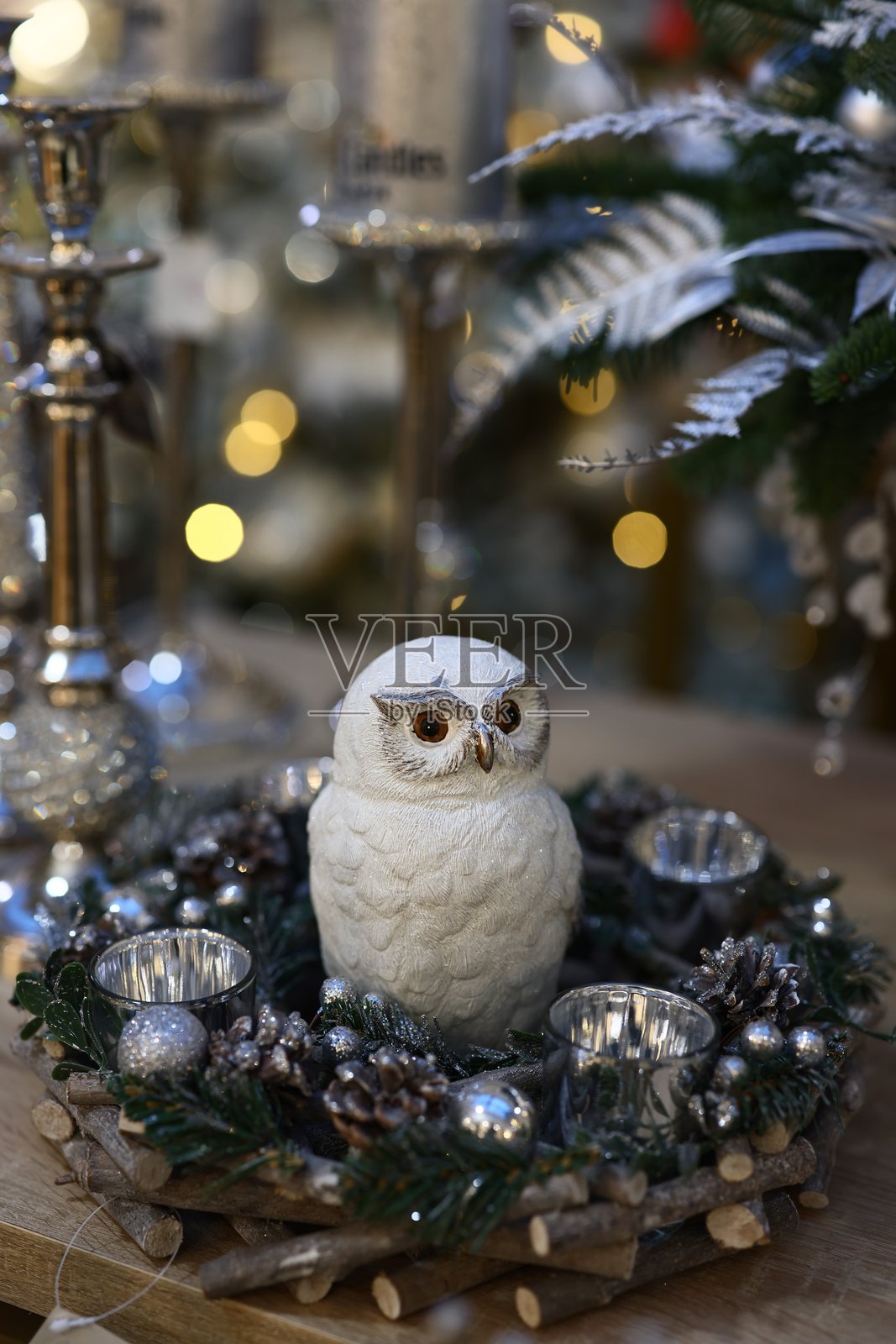 这是一个迷人的冬季仙境装饰,展示了一只优雅的白色猫头鹰雕像。照片摄影图片