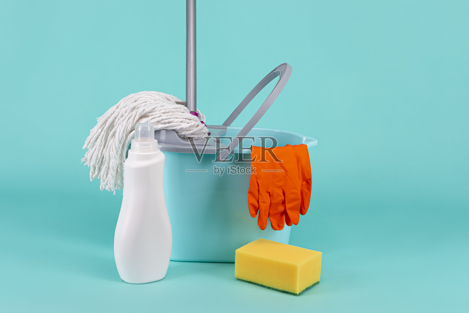 一套多样的清洁配件,包括桶、拖把和清洁用品,背景为室内的青绿色。照片摄影图片