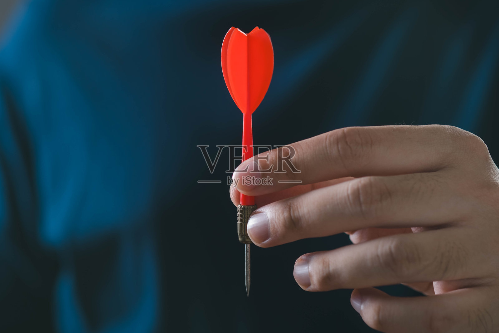 一只手握着红色飞镖的特写,象征着在游戏或运动中的精准和专注。照片摄影图片