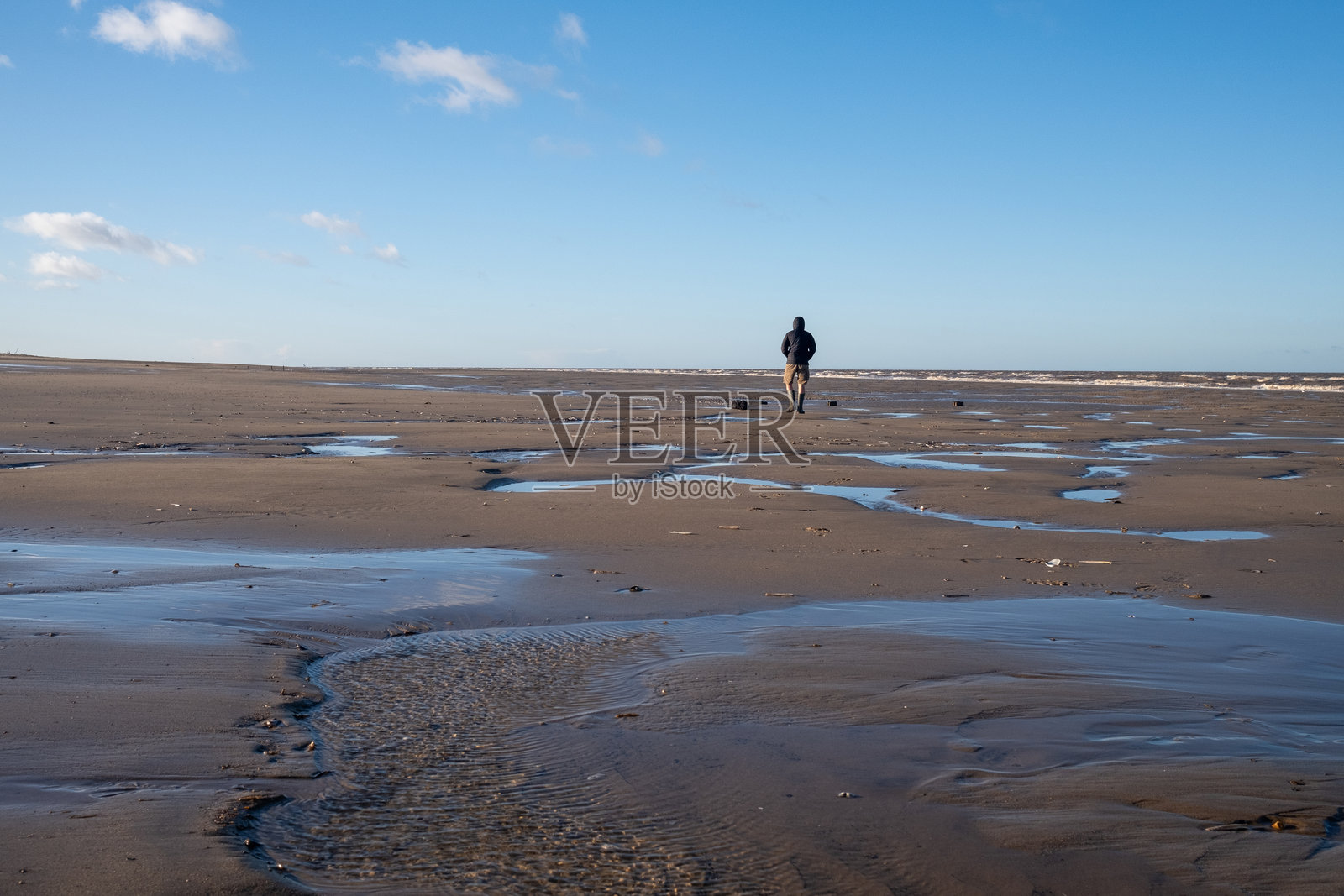 孤独的男人在冬季的空旷海滩上漫步照片摄影图片