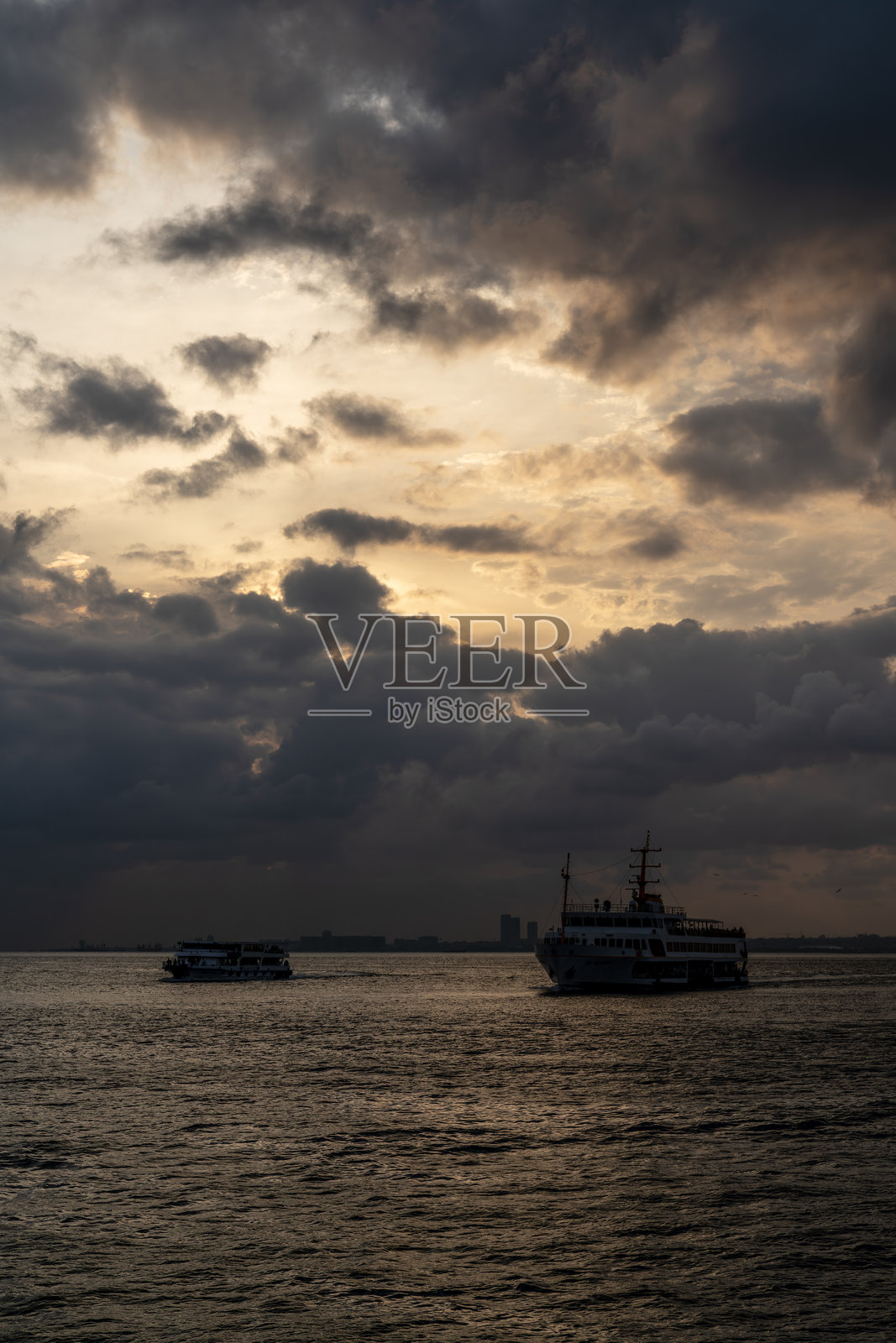 伊斯坦布尔博斯普鲁斯海峡,两艘船只在戏剧性的天空下航行,黄昏时分的博斯普鲁斯海峡与两艘船。照片摄影图片