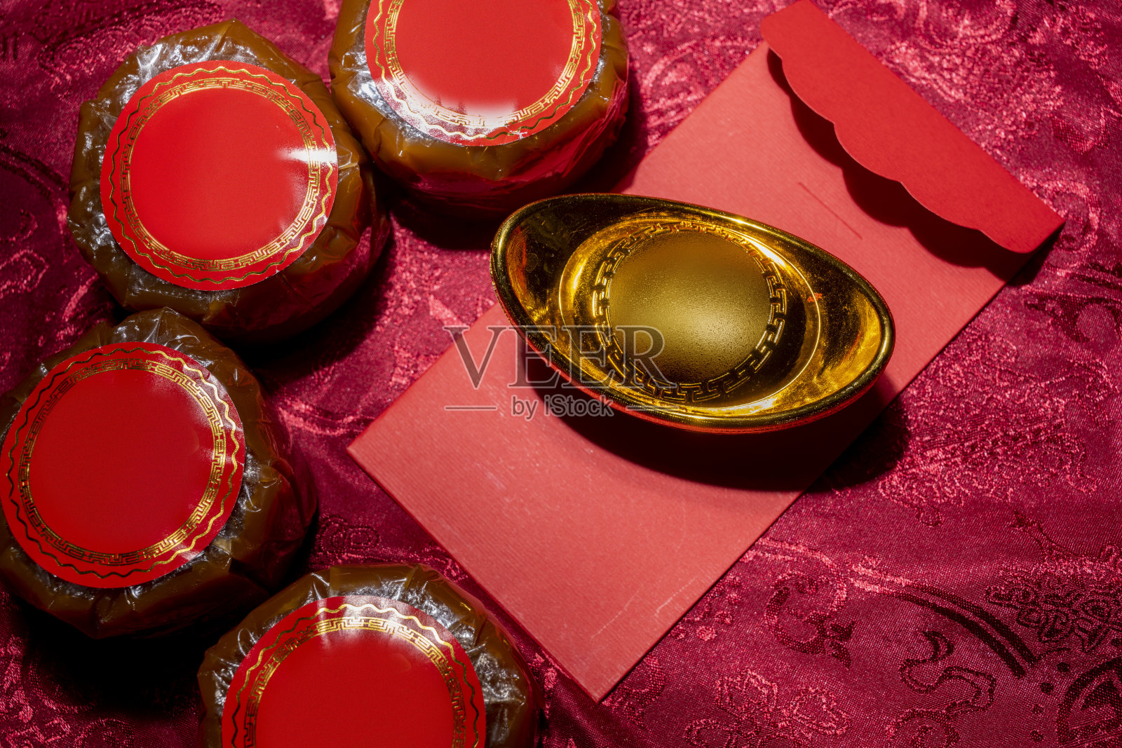 春节年糕与红包和金元宝在红色布背景上照片摄影图片