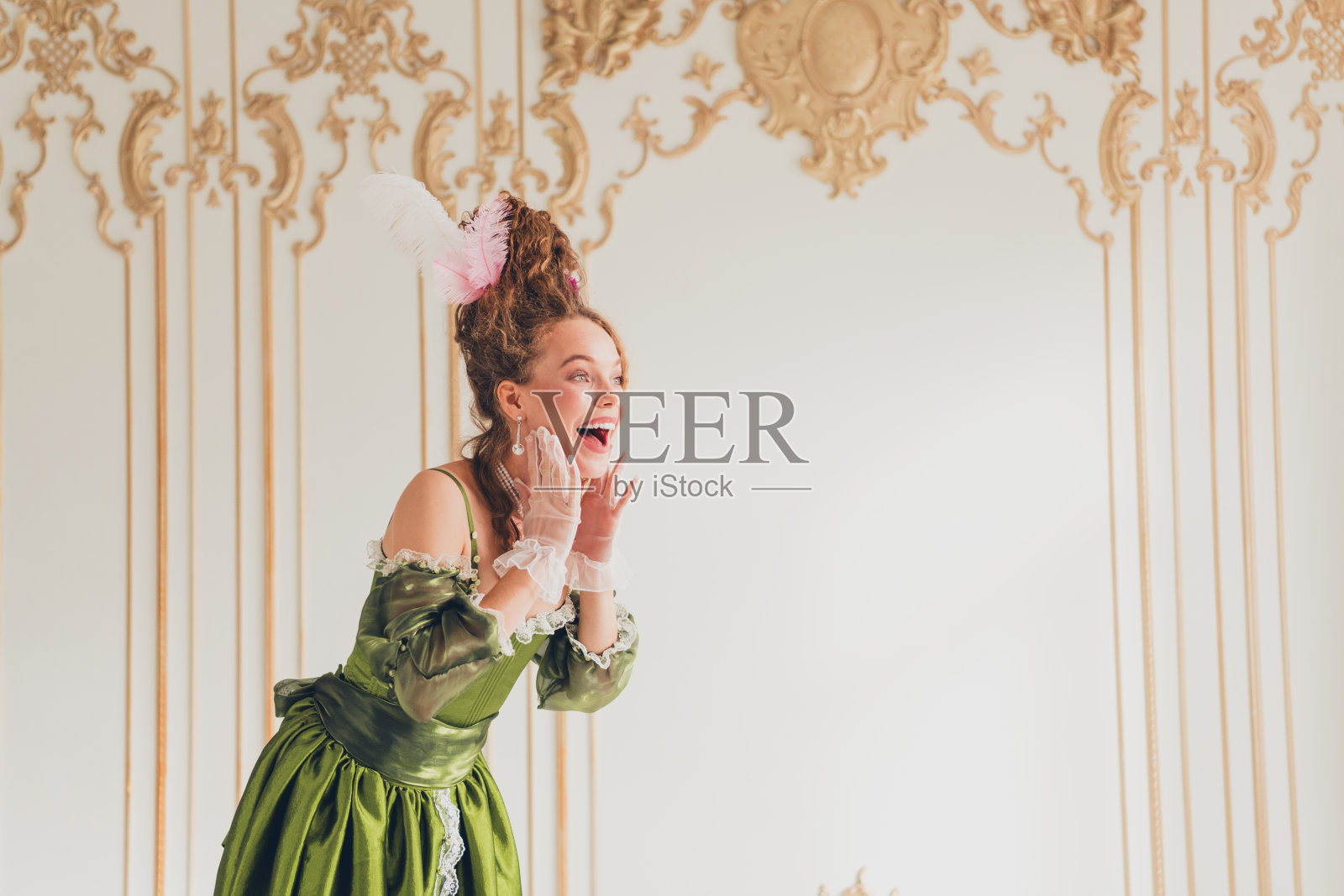 年轻女性身着奢华的巴洛克服装,站在展示历史与现代对比的宏伟室内。照片摄影图片