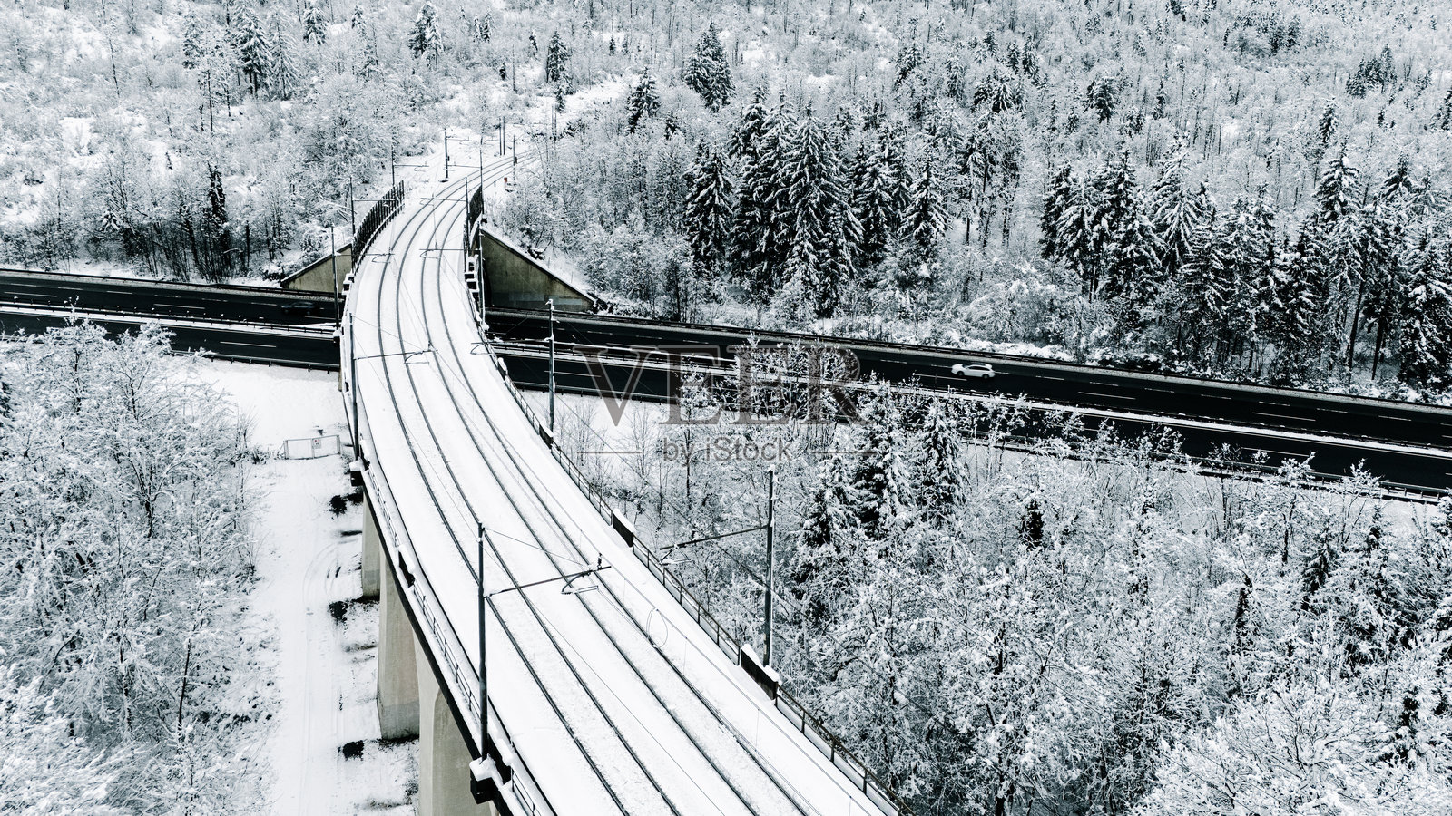 冬季森林中的雪覆盖铁路桥横跨公路照片摄影图片