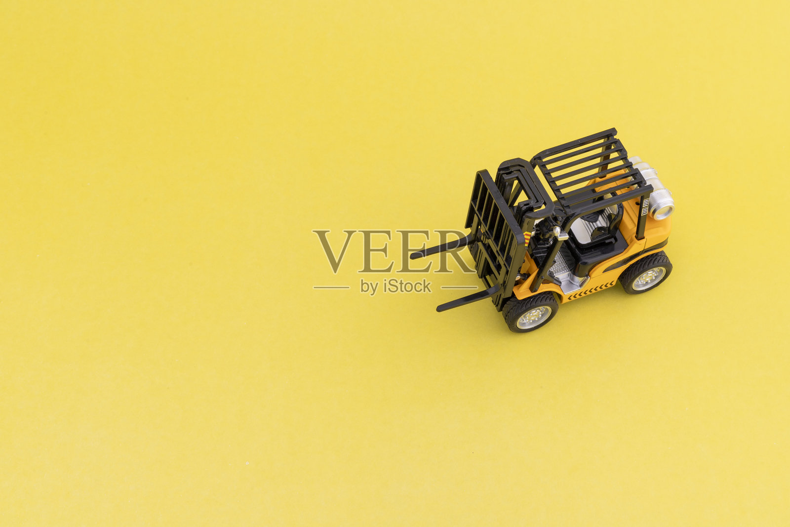 黄色背景上的叉车模型,留有文本空白。照片摄影图片
