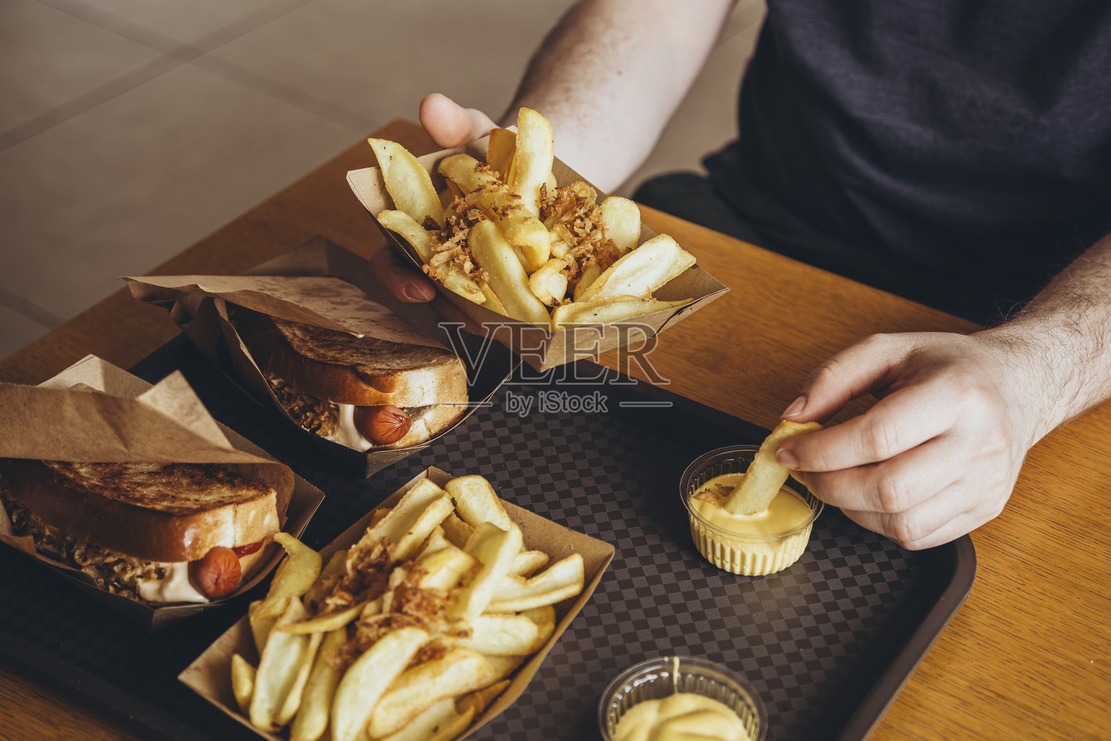 一个男人在酒吧或快餐咖啡馆里吃脆皮土豆配奶酪酱。照片摄影图片