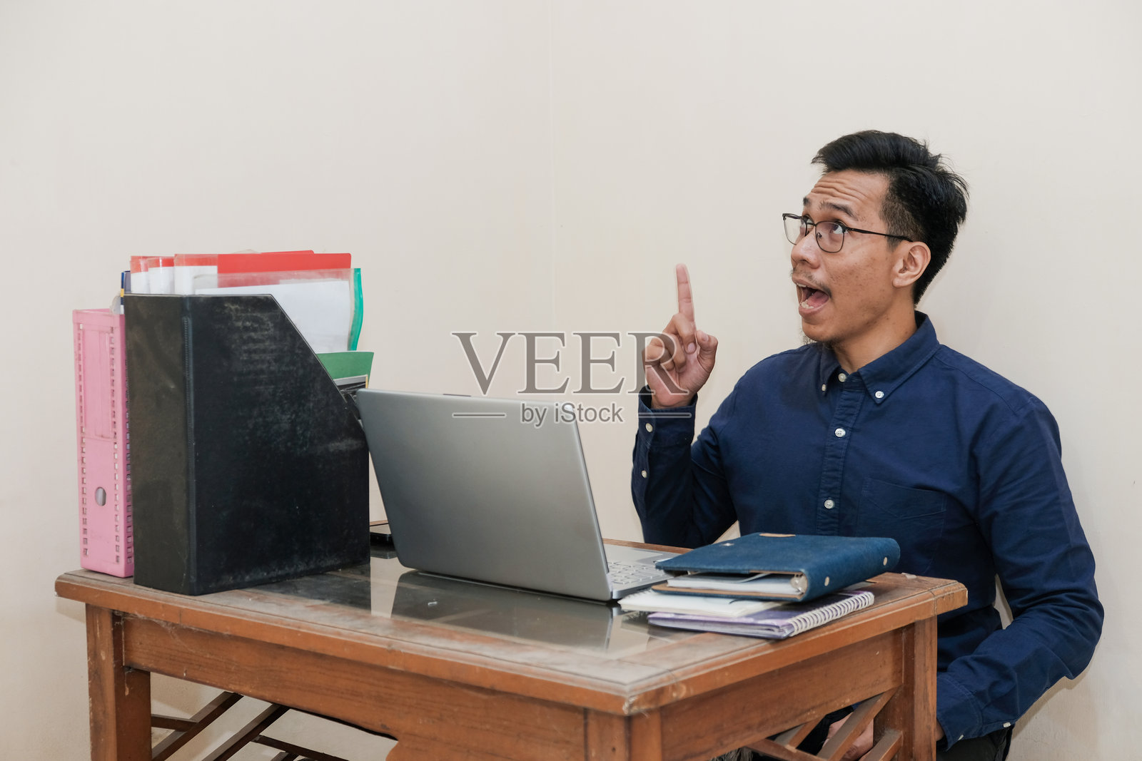 微笑快乐的东南亚男子坐在家中办公室前,举起手指在笔记本电脑前工作照片摄影图片