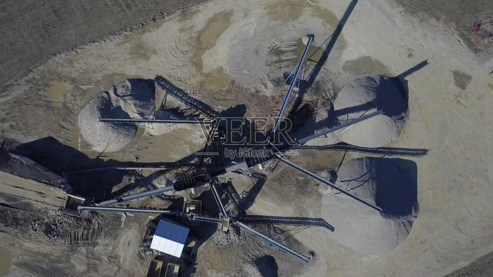 用于提取和分类碎石的设备元素。建筑材料的生产。用于处理石头和岩石的金属结构。输送带下的碎石渣。照片摄影图片