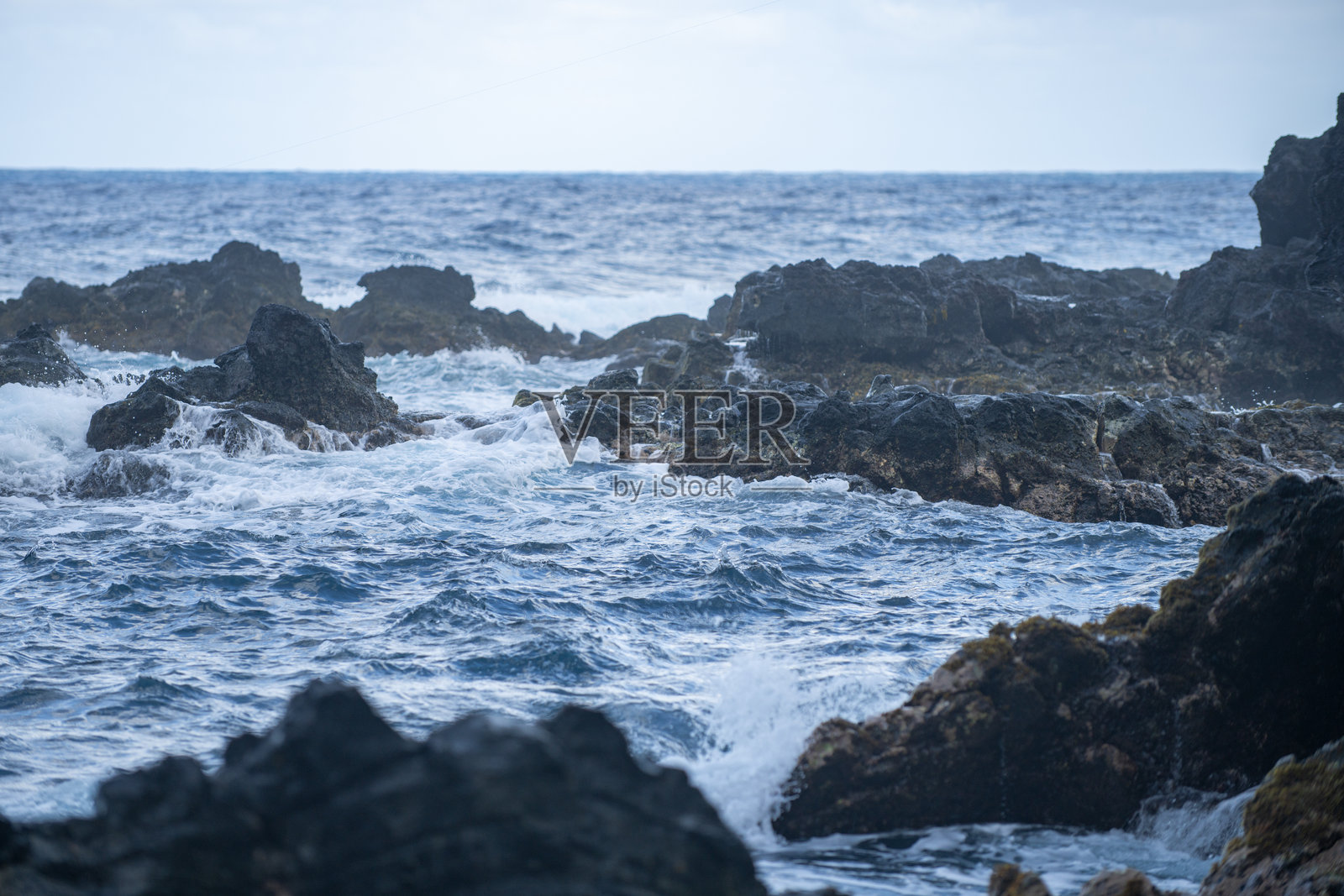 海浪撞击海滩的岩石,海水在海面上飞溅。海景。海浪撞击岩石海岸时溅起的水花。照片摄影图片