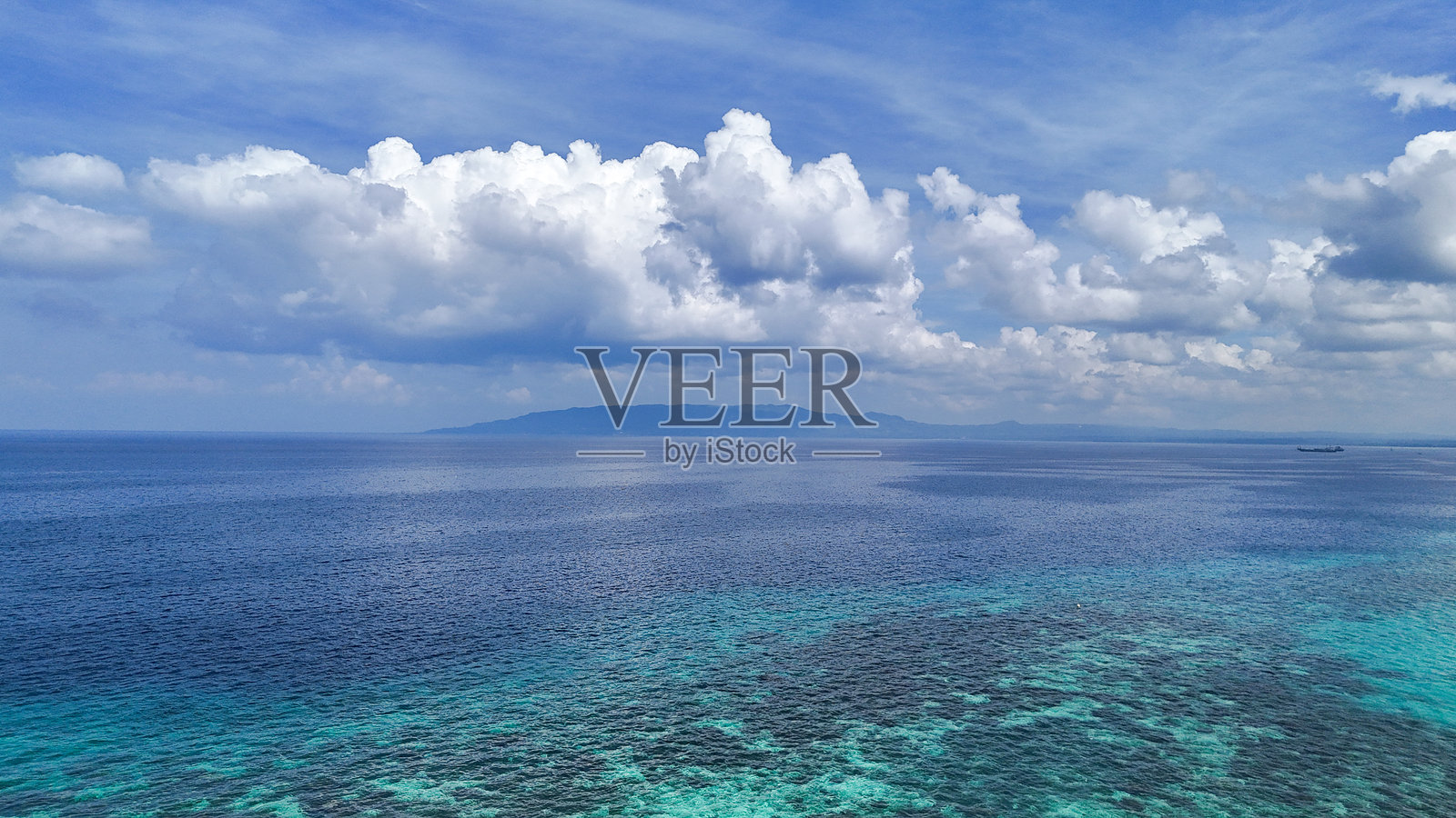 热带海景,碧蓝的海水和远处的岛屿在生动的天空下照片摄影图片