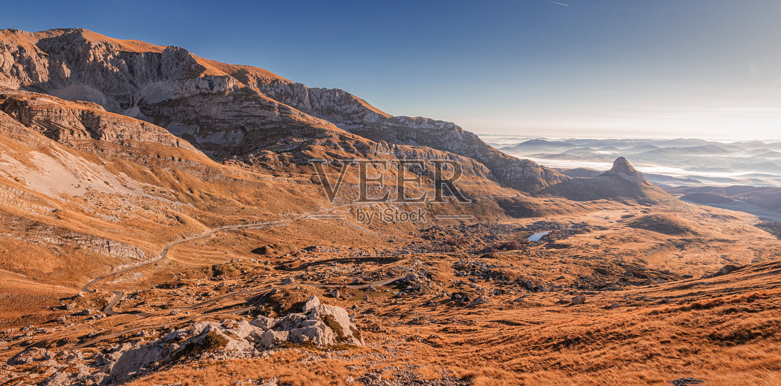 金色时光照亮了黑山杜尔米托国家公园的山谷和山脉,蜿蜒的道路穿行其间。照片摄影图片