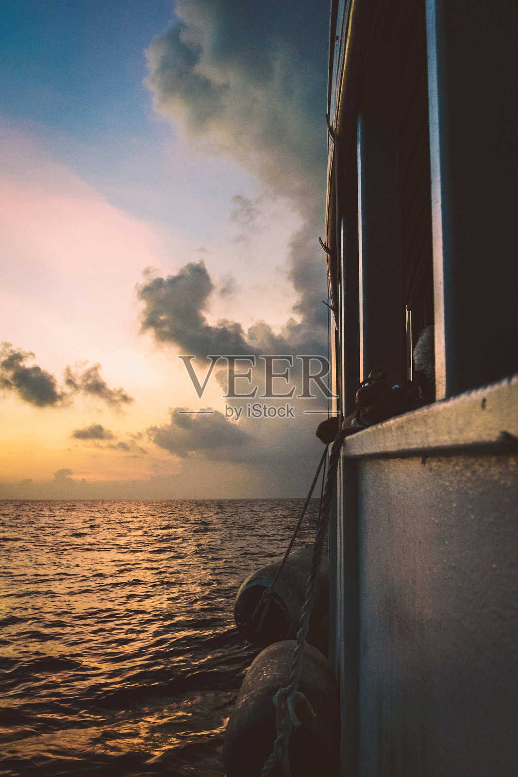 马尔代夫的日落,水面上映出太阳的倒影,天空中有蓝色和橙色的云彩。照片摄影图片