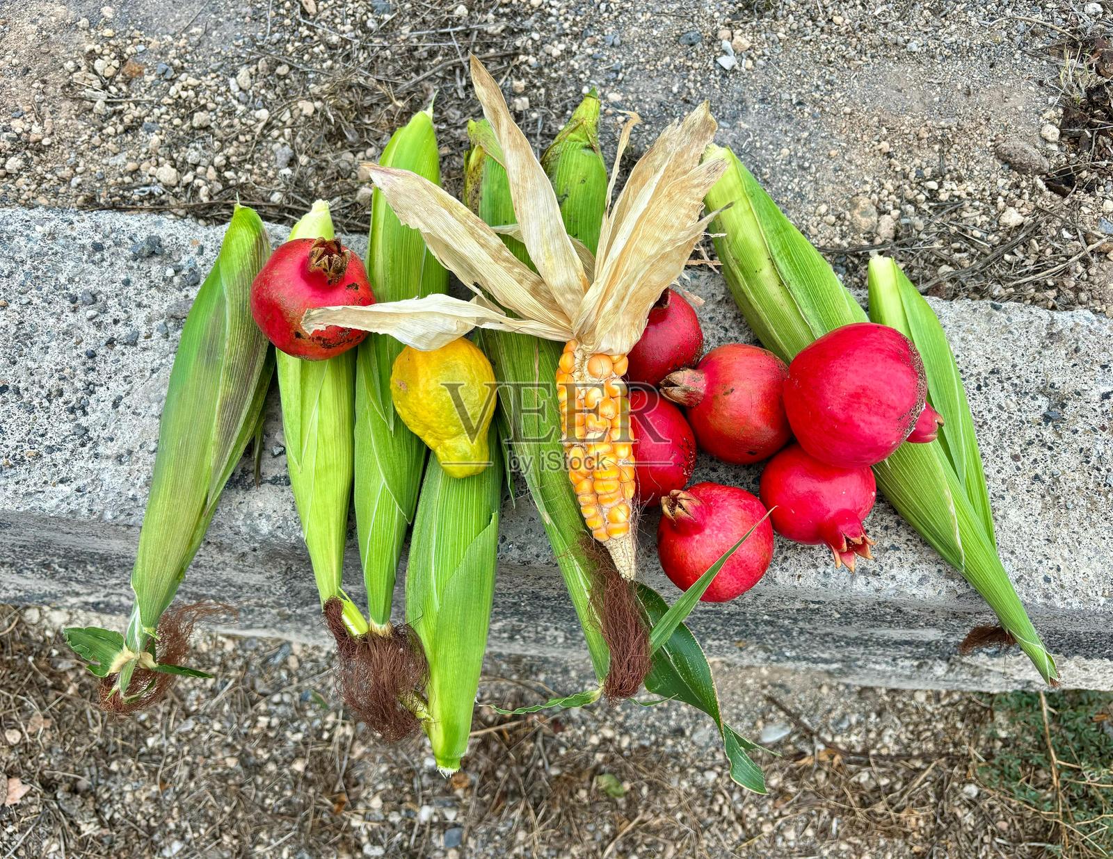一堆玉米、石榴和番石榴在石质表面上特写,丰收季节照片摄影图片
