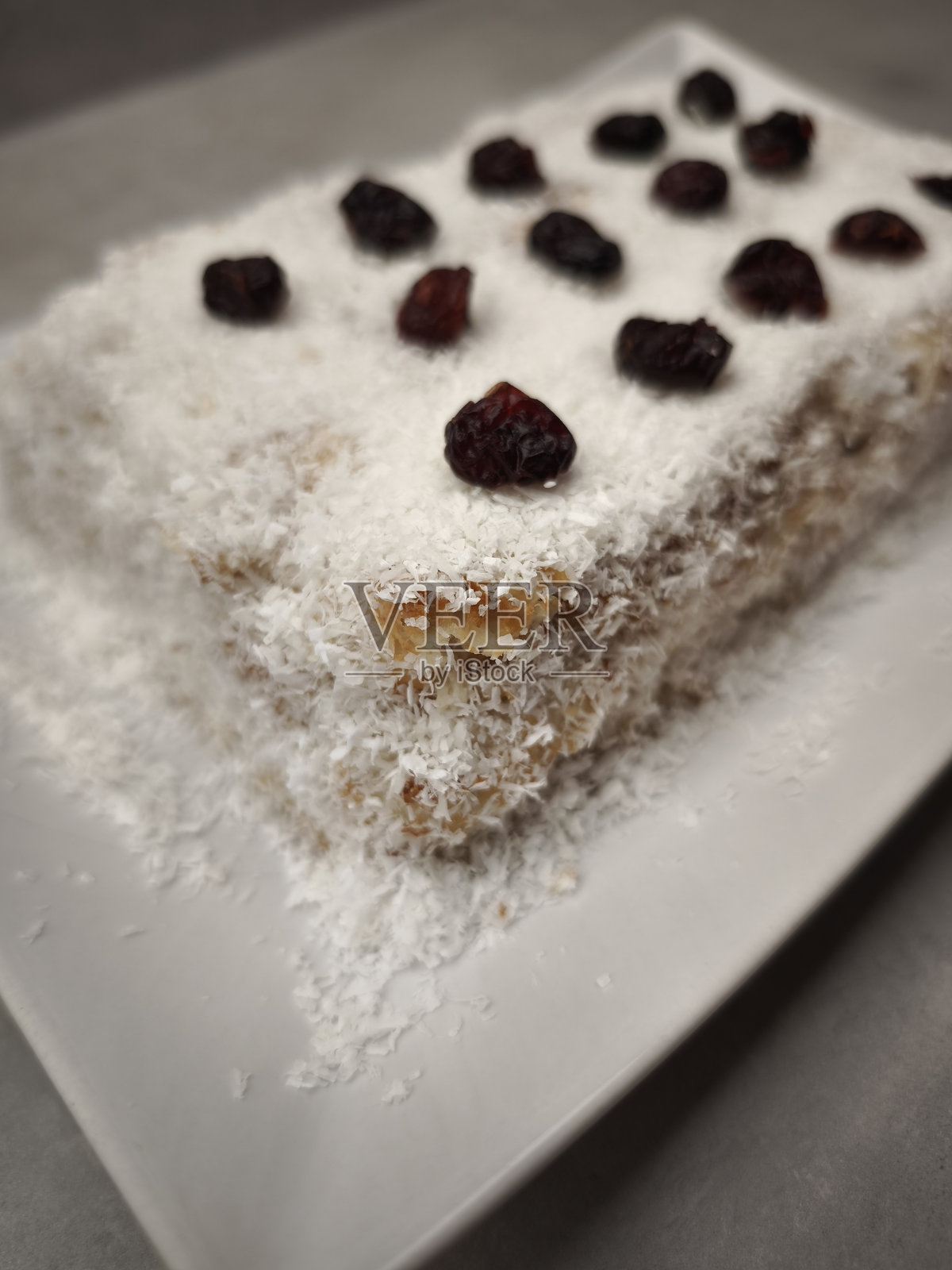 美味的圣诞椰子布丁,上面撒有干蔓越莓,摆放在白色盘子上,适合用作开胃菜、跨年晚宴、圣诞节或生日派对食品。照片摄影图片