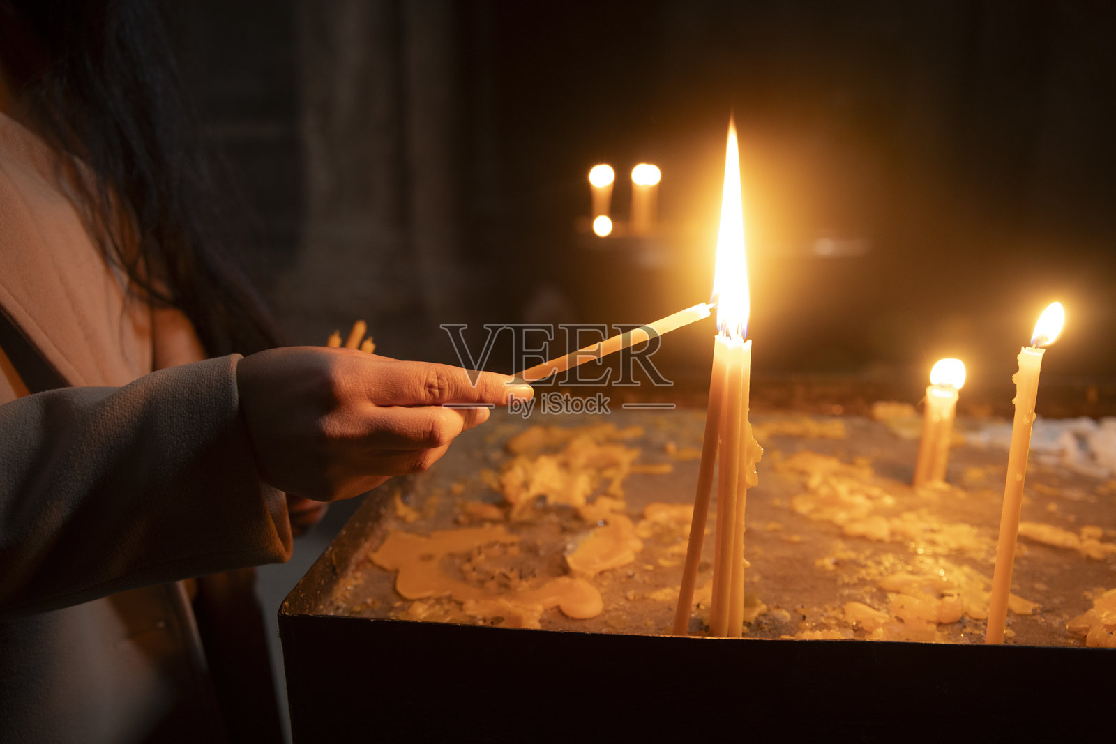 一位女性在教堂点燃蜡烛。亚美尼亚照片摄影图片