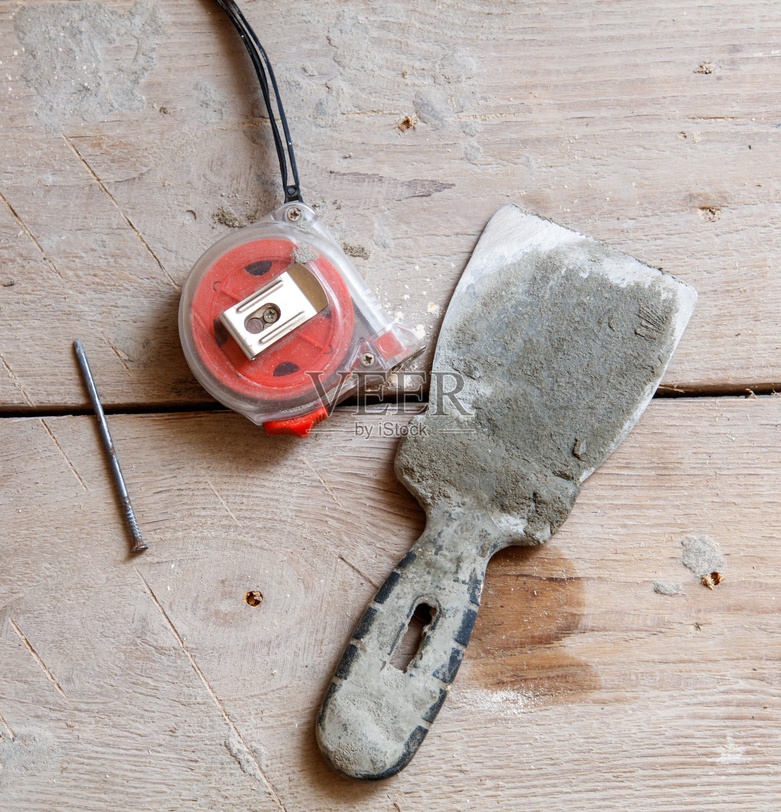 一卷卷尺和一把泥刀放在木质表面上照片摄影图片