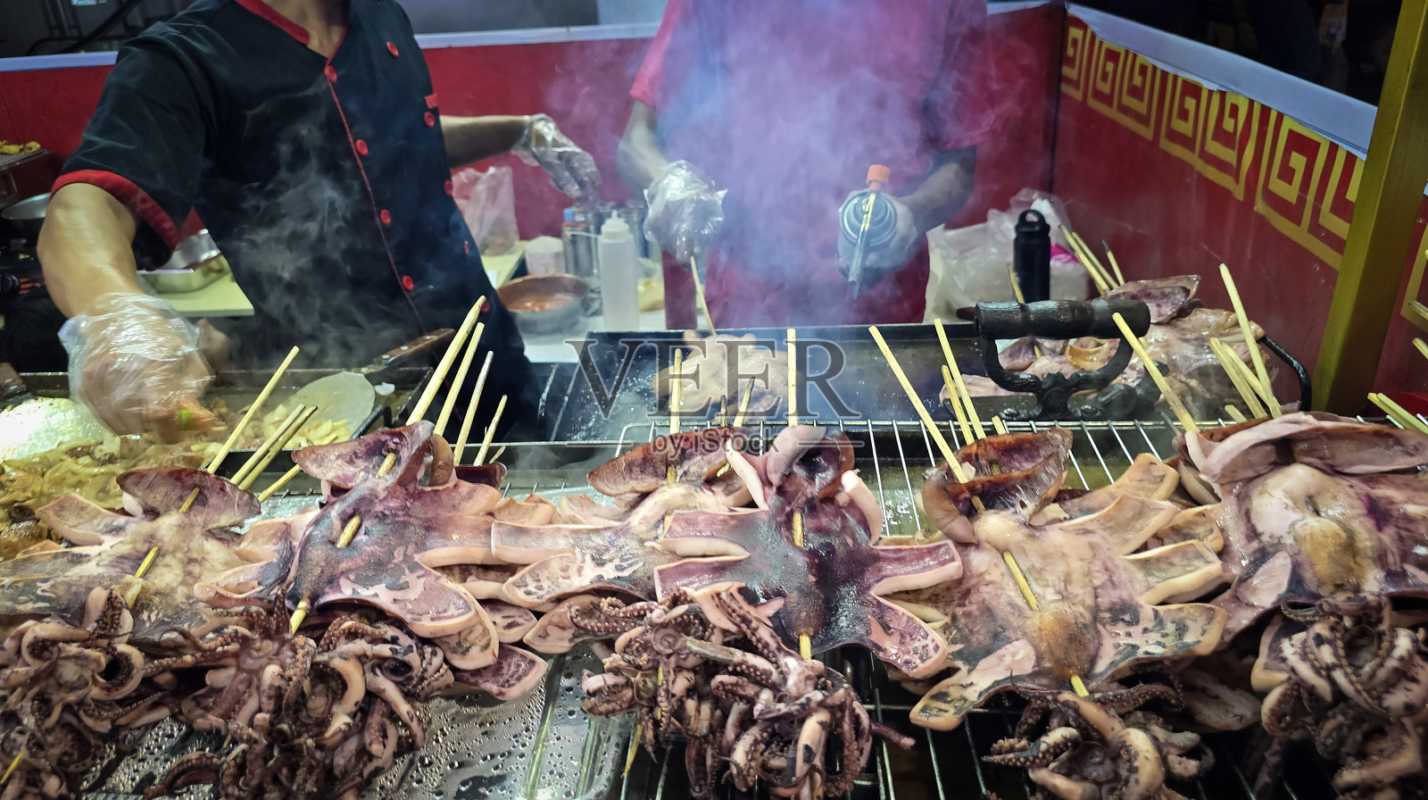 新鲜烤制的烧烤鱿鱼串在亚洲街头美食市场展示,展现了丰富的烹饪传统。照片摄影图片