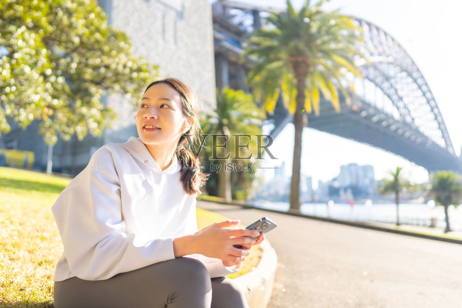 亚洲女性在城市中慢跑时使用智能手机。照片摄影图片