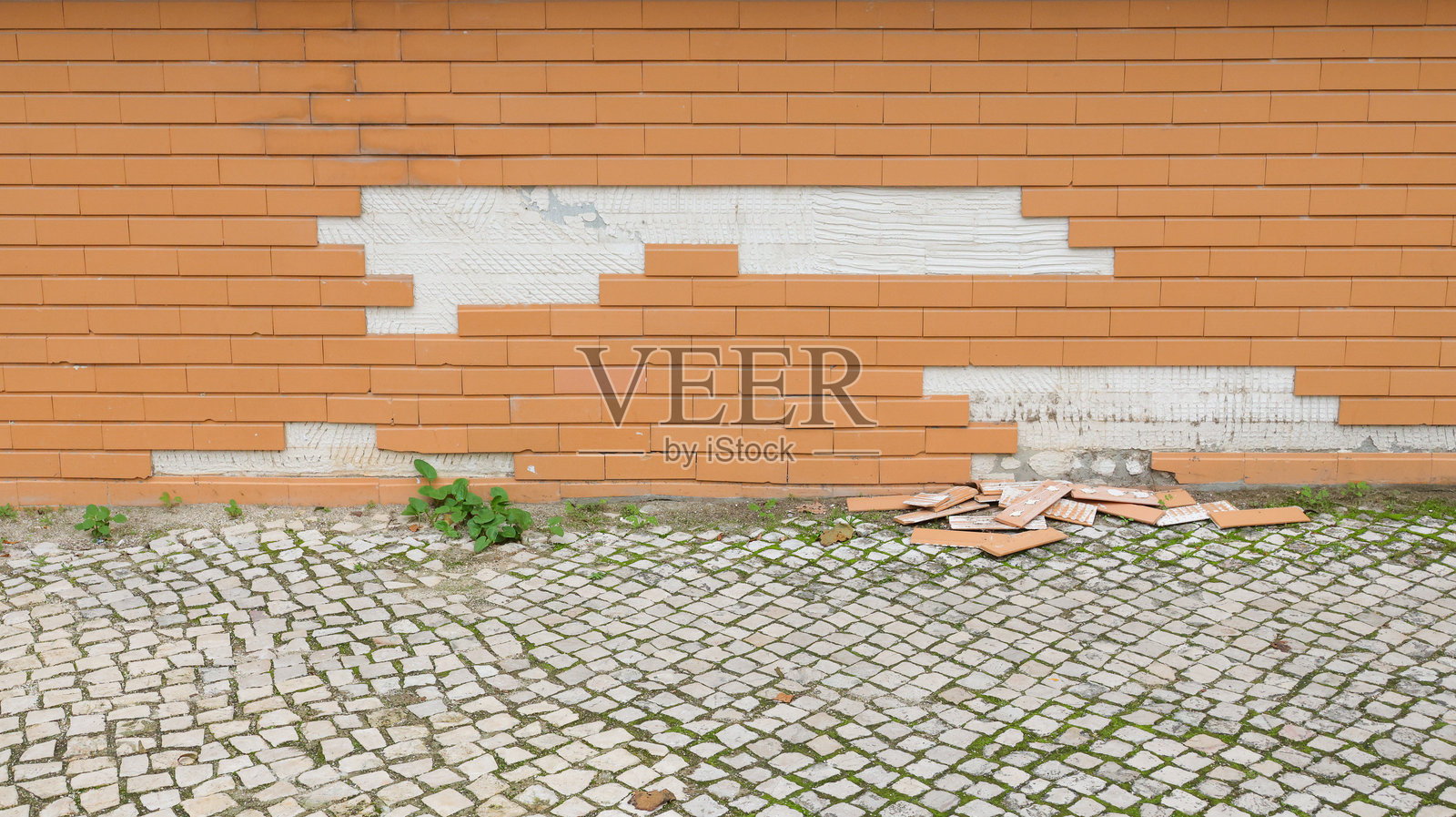 破碎的砖瓦从建筑外立面掉落到鹅卵石街道上照片摄影图片