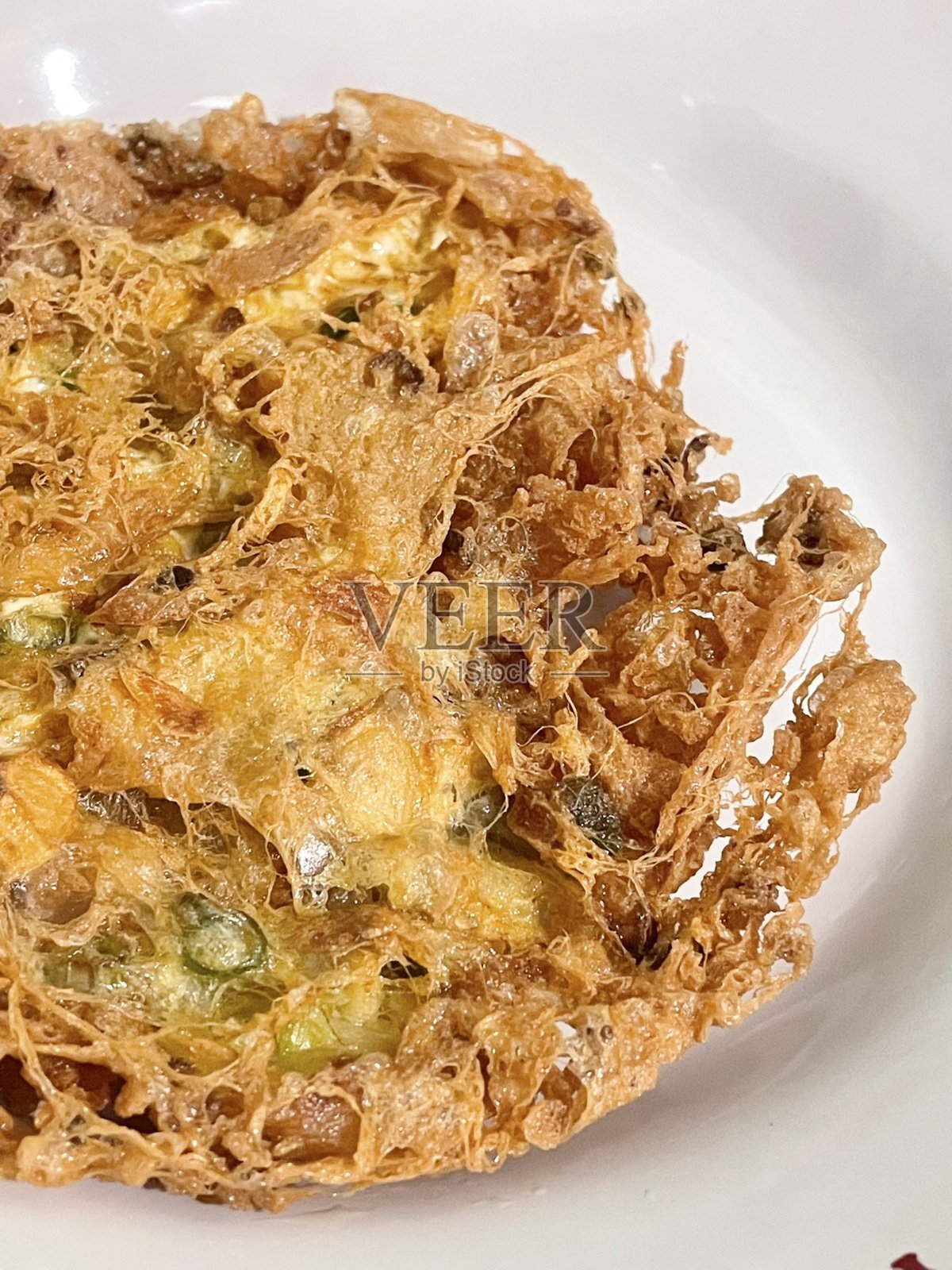 脆边煎蛋或称为telur barendo,蛋黄柔软,金棕色的边缘波浪状,盛放在简单的白色盘子上。脆嫩的完美结合。照片摄影图片