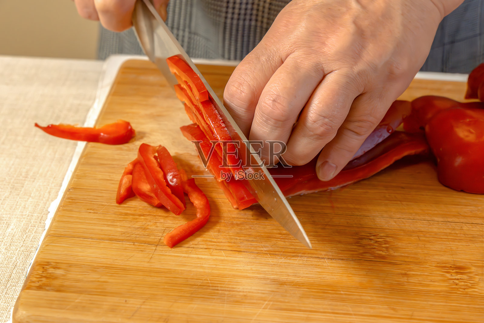 厨师在切菜板上将甜红椒切成小块。特写镜头照片摄影图片