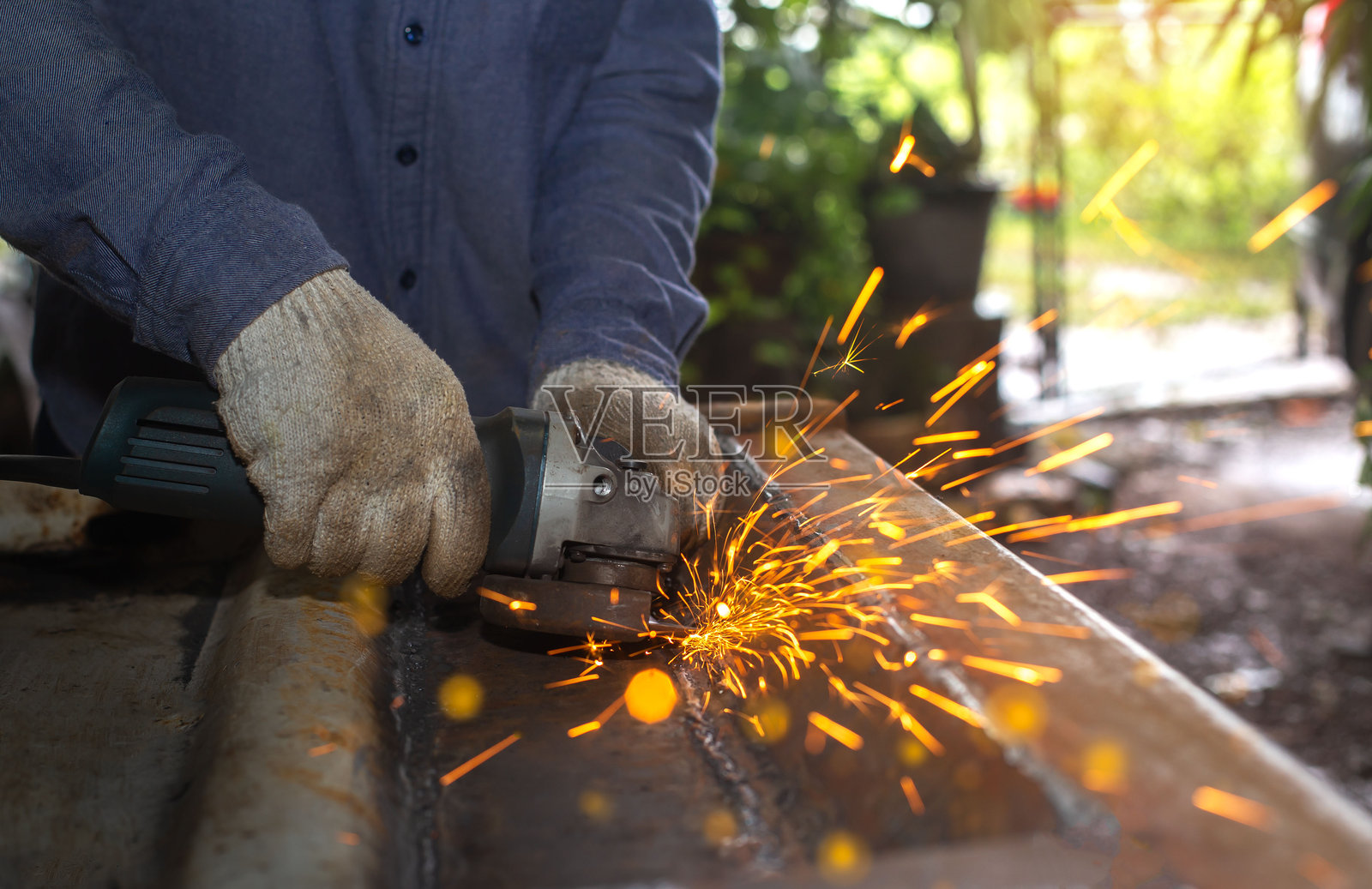 重工业工程厂房内部,工业工人在使用角磨机切割金属管。照片摄影图片