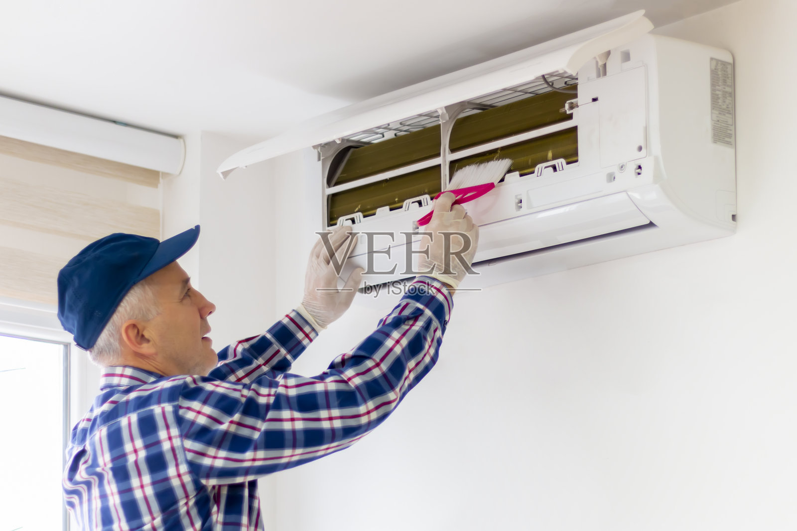 一名男子正在清洁家用空调的过滤器。照片摄影图片