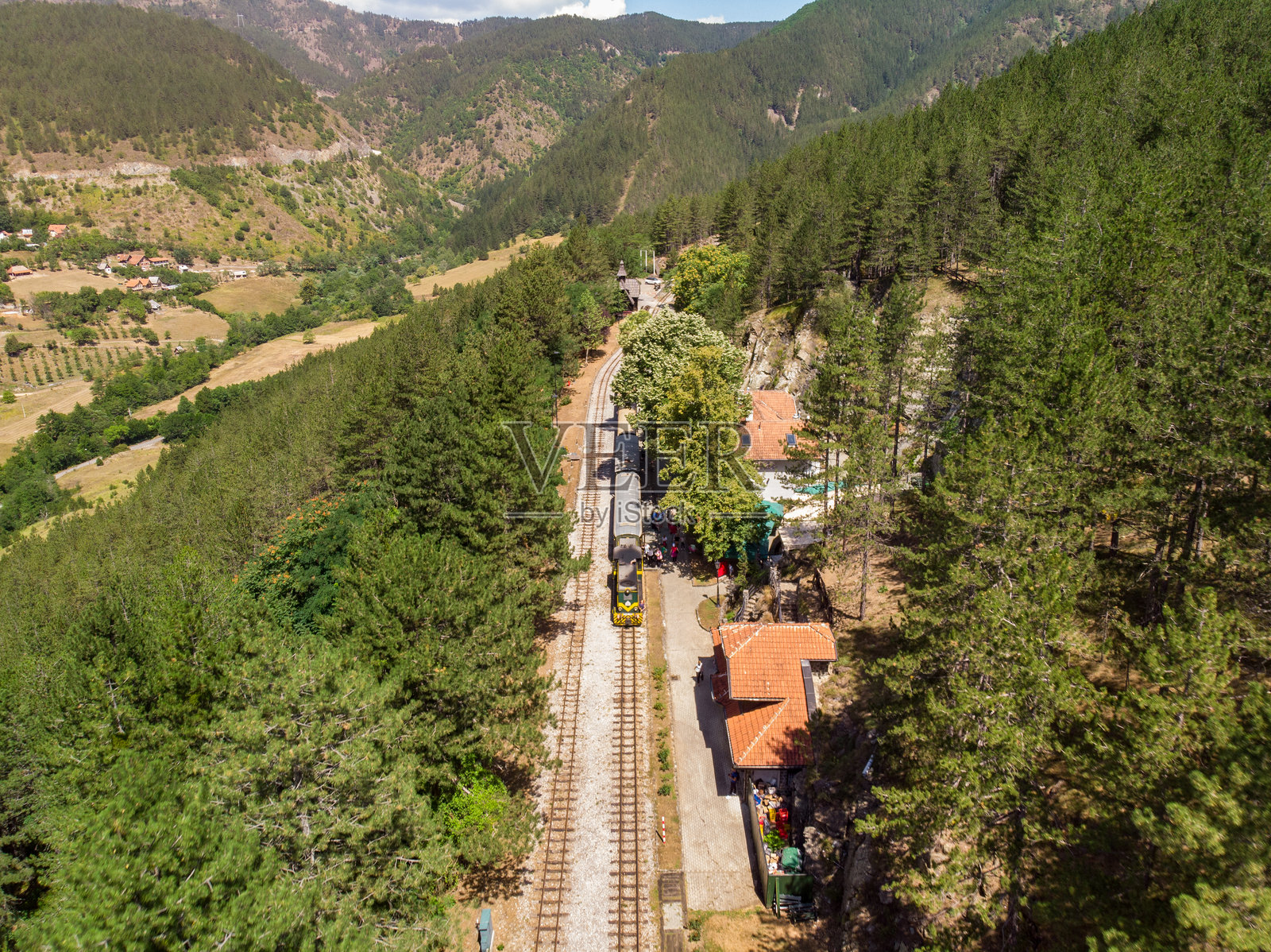 窄轨火车穿过风景如画的山区,四周环绕着郁郁葱葱的森林照片摄影图片