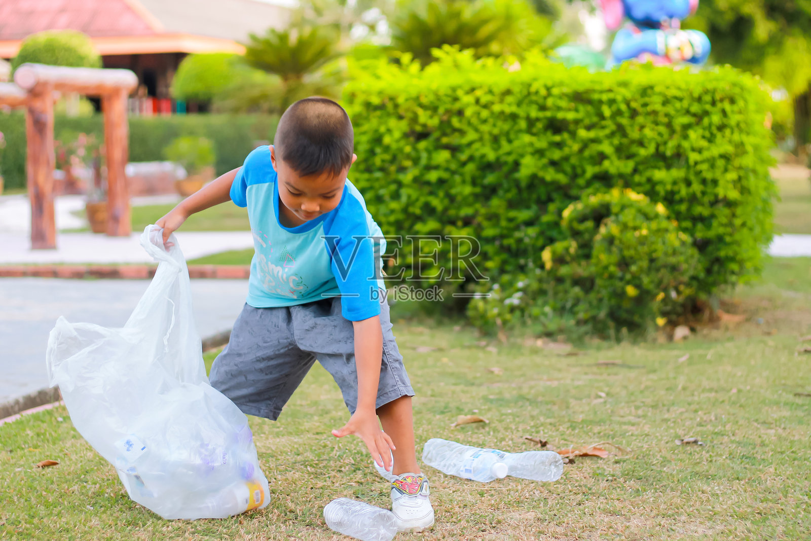 男孩在公园里捡垃圾照片摄影图片