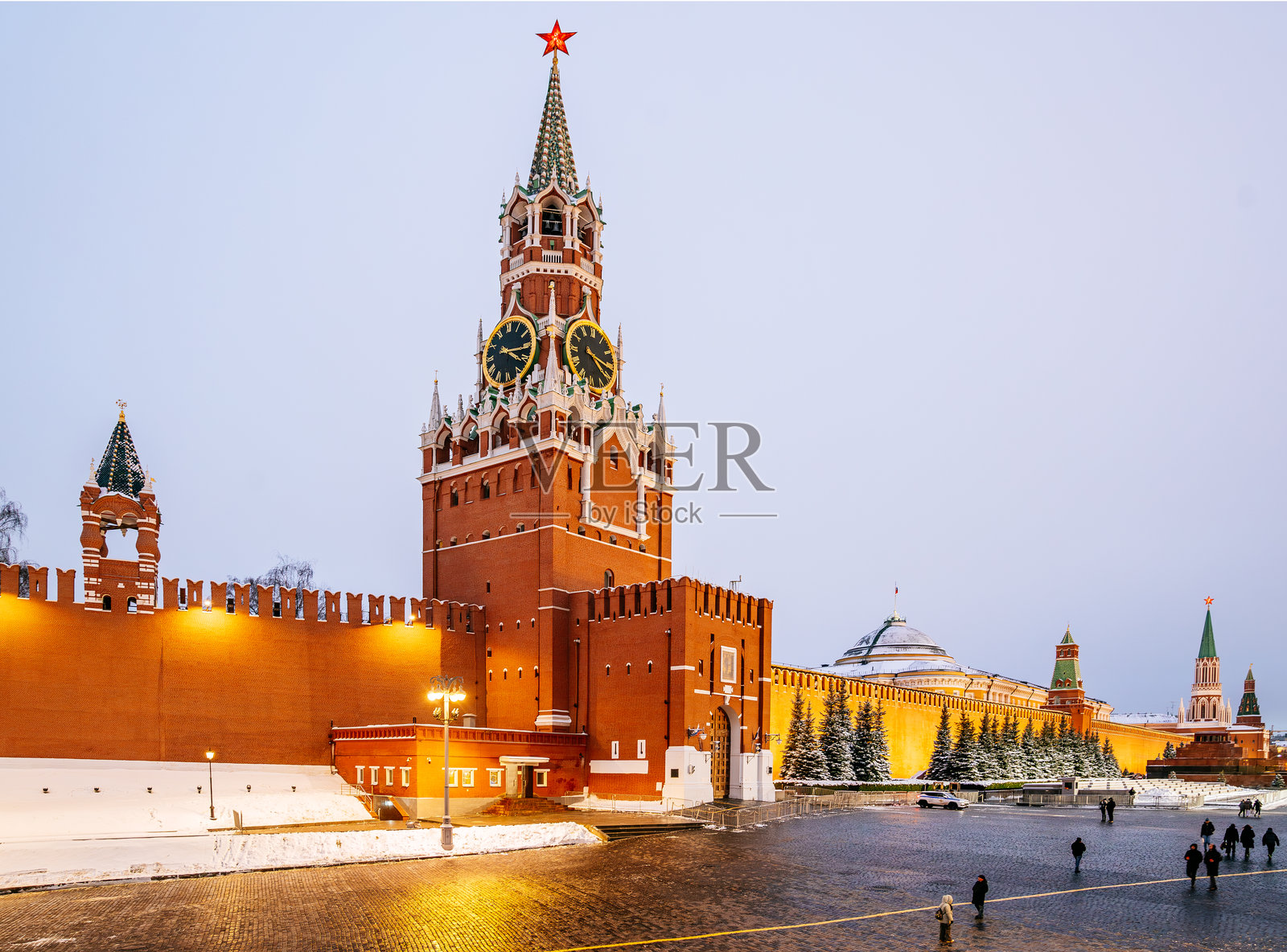 莫斯科的斯巴斯卡塔和克里姆林宫墙在晚间灯光下的特写,周围是覆盖着雪的路面。照片摄影图片