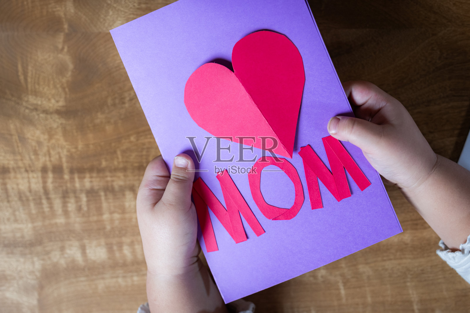 一个孩子的手握着一张写有“妈妈”和心形图案的卡片照片摄影图片