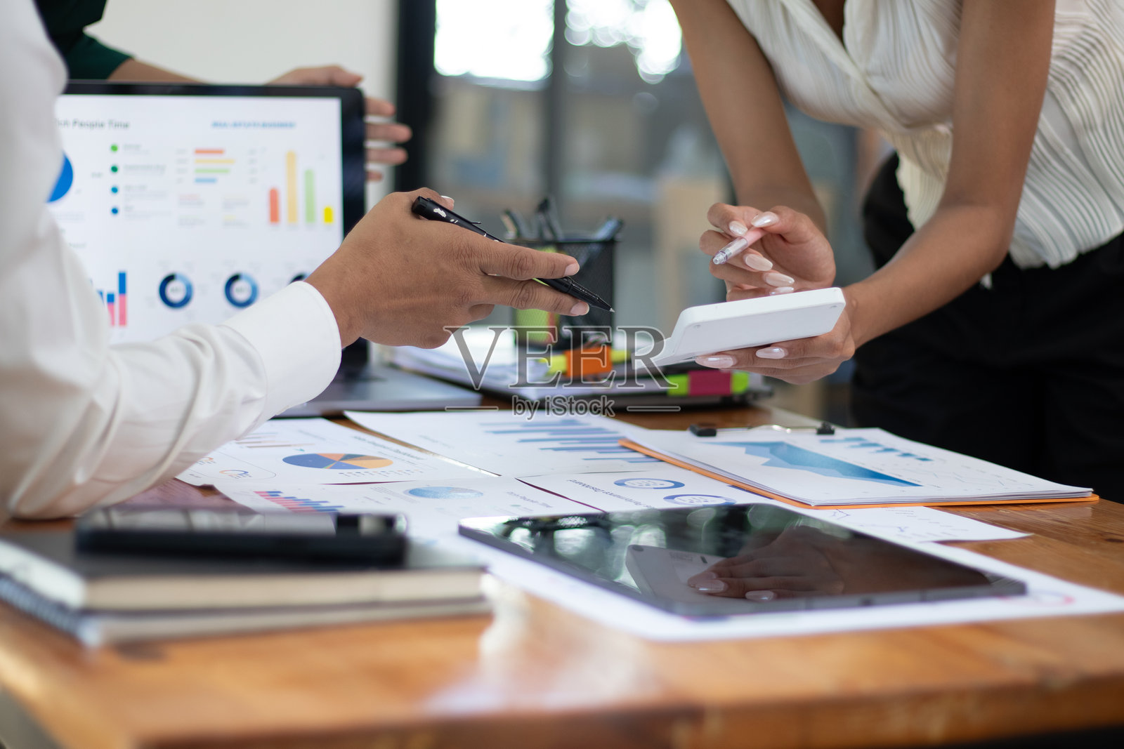 一组亚洲商人分析提议的销售市场细分。交易专家在办公室大堂使用纸质数据图表。照片摄影图片