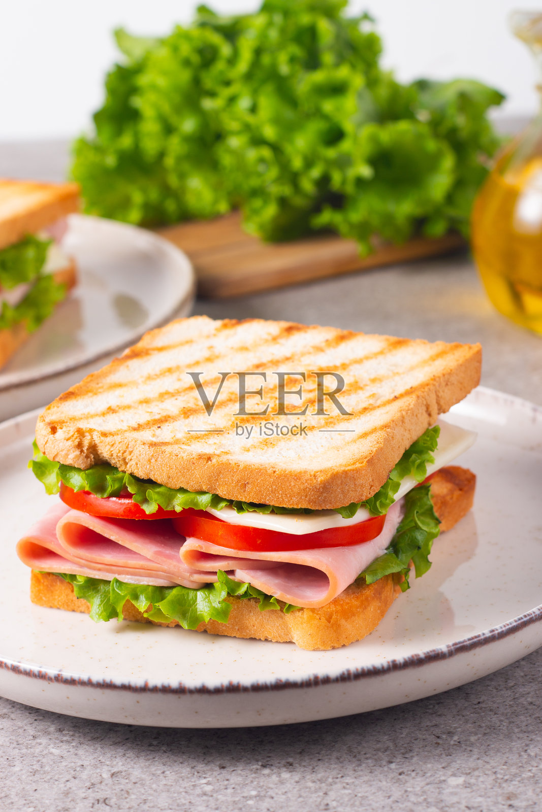 特写两份夹有培根、萨拉米香肠、意大利火腿和新鲜蔬菜的三明治,放在乡村风格的木砧板上。俱乐部三明治概念照片摄影图片