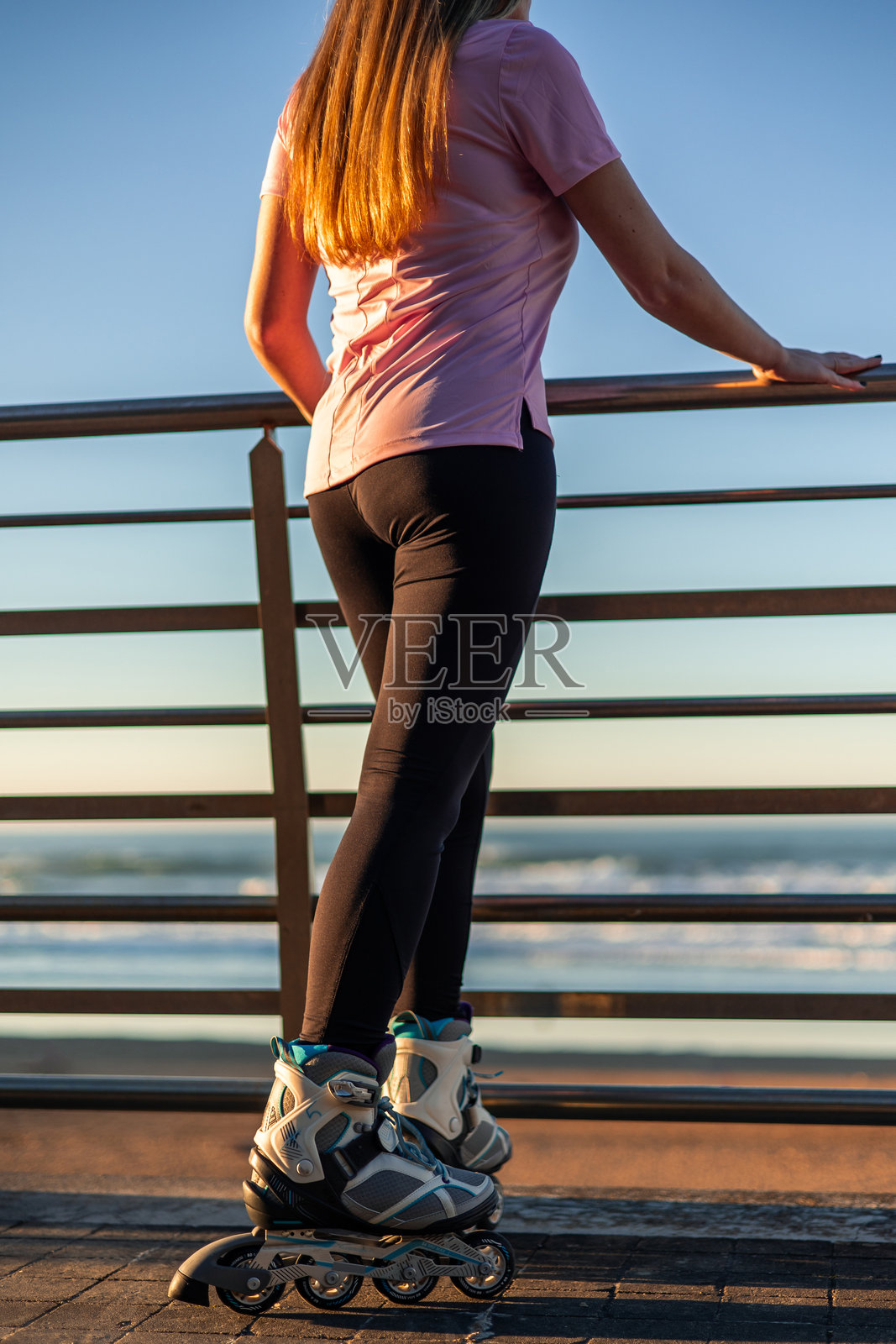 穿着直排轮滑鞋的女人在日落时分望着大海照片摄影图片
