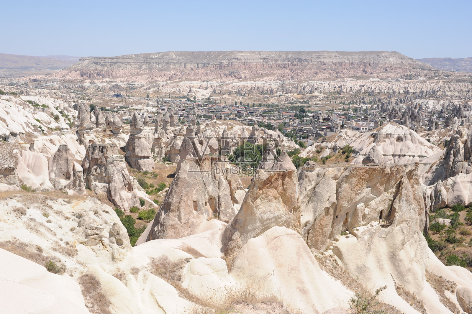 卡帕多奇亚(Cappadocia)安纳托利亚(Anatolia)土耳其的鸽子谷(Güverçinlik Vadisi)岩石形成,夏日晴空万里,远处是格雷梅镇(Göreme)。照片摄影图片