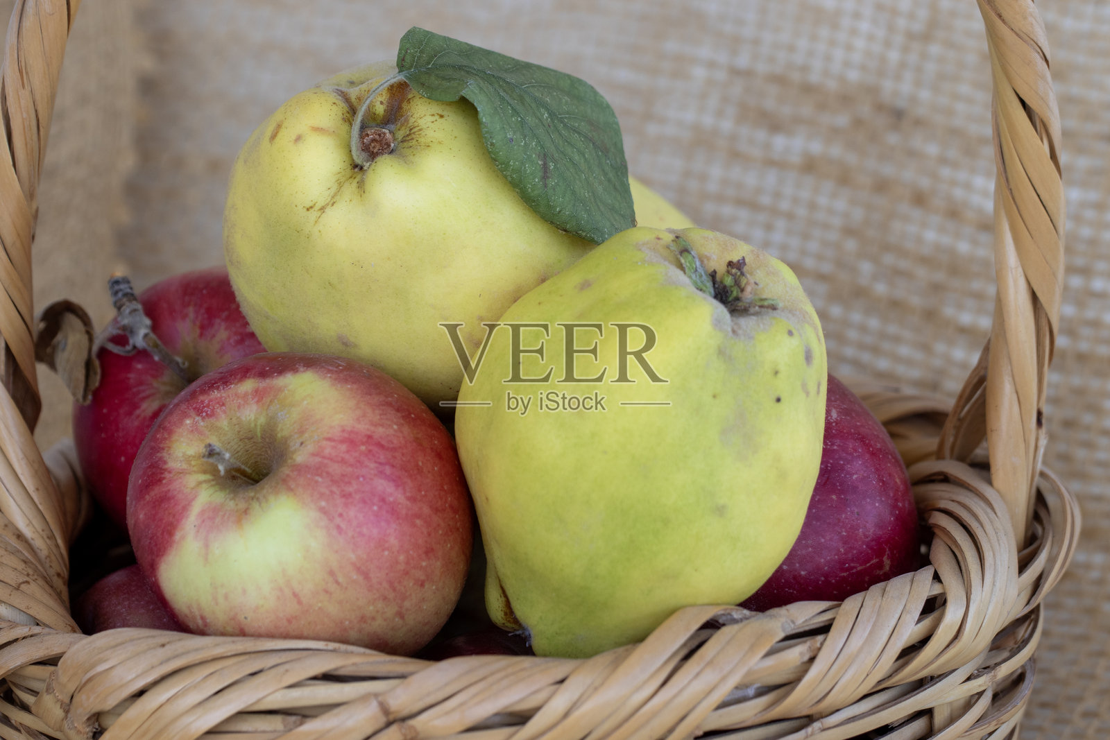 柳条篮中的苹果、榅桲和石榴。照片摄影图片