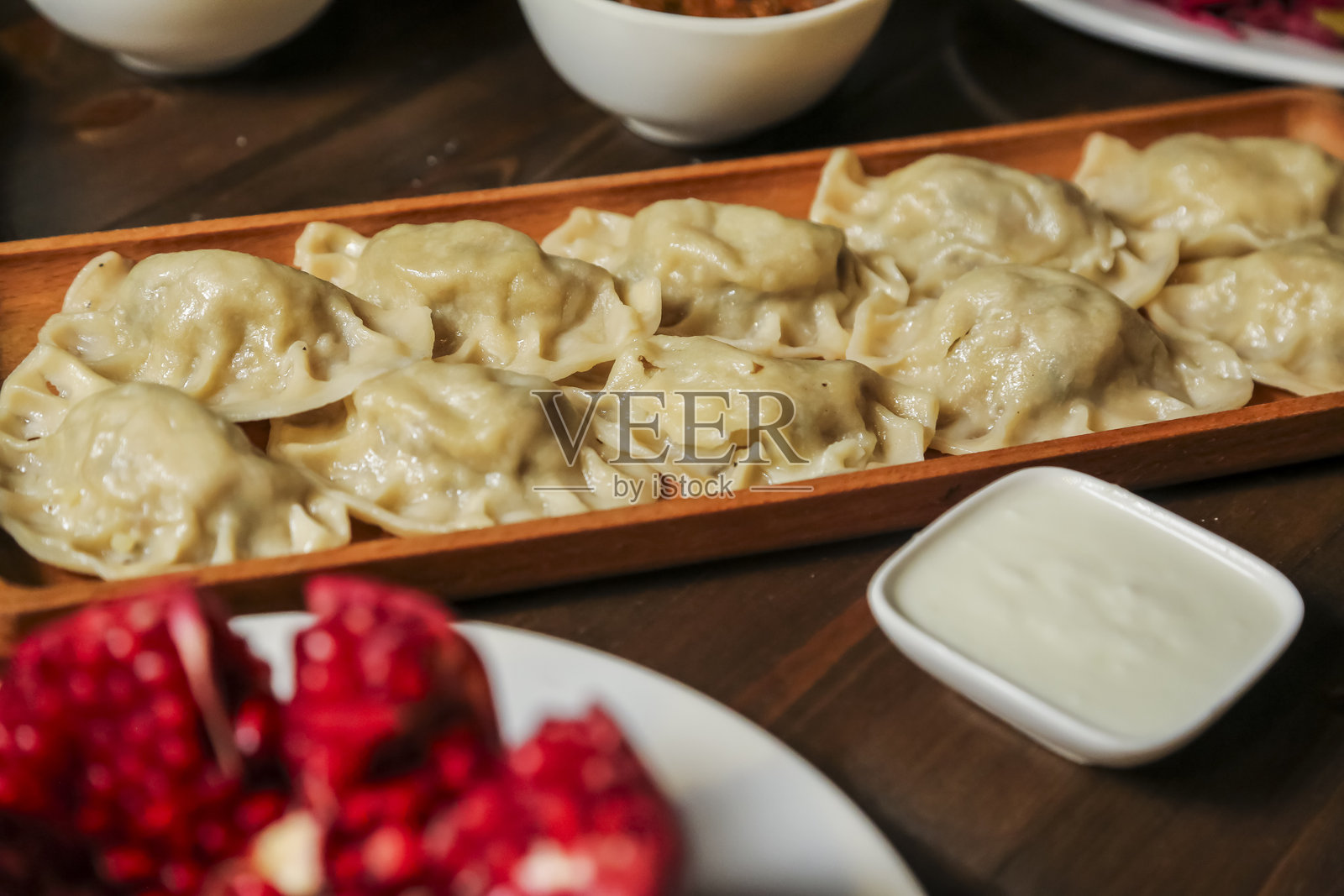美味的饺子配上蘸酱,摆放在木质托盘上照片摄影图片