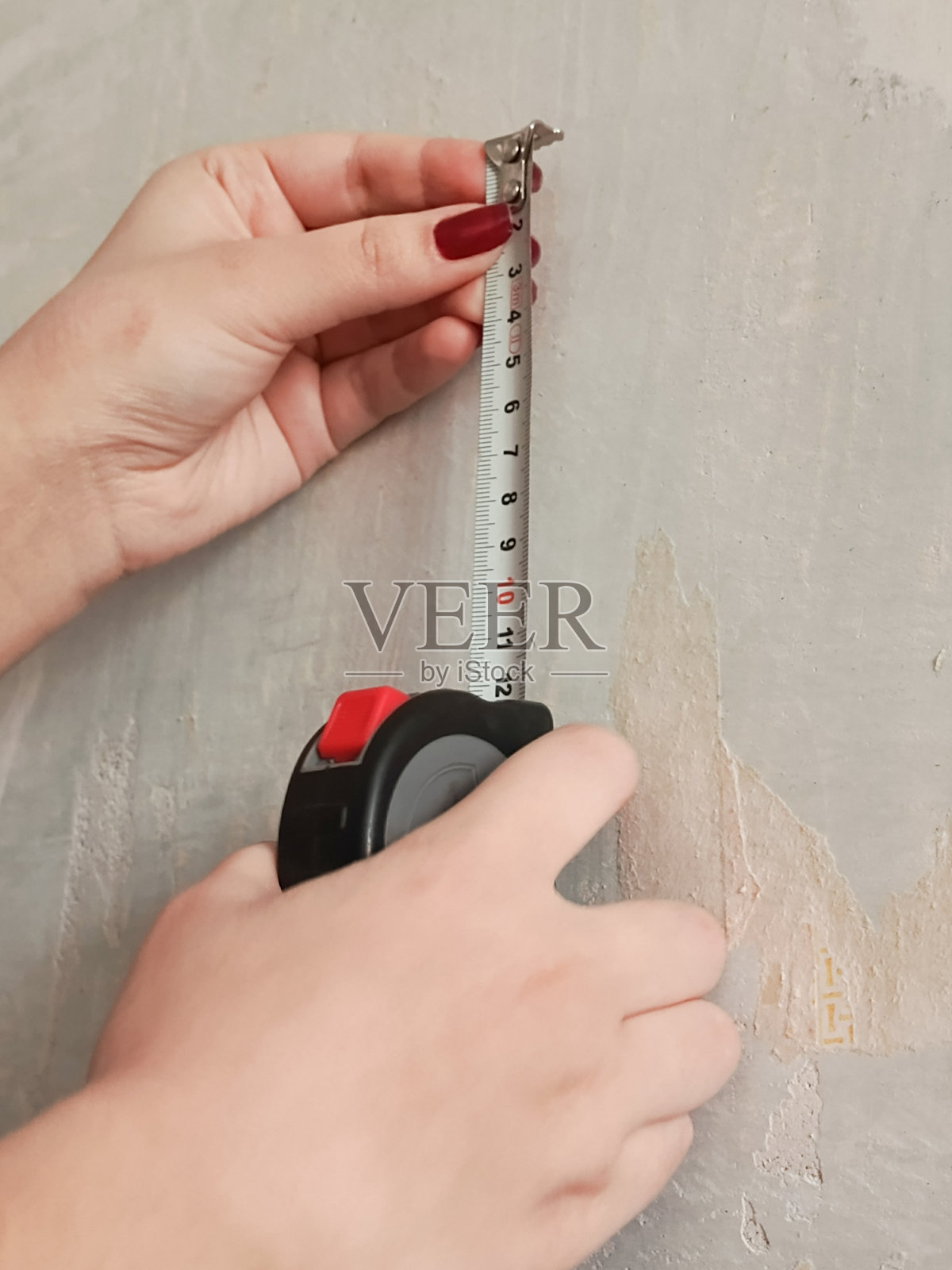 手用卷尺测量混凝土墙。卷尺以厘米为单位。房屋的建筑项目。墙壁和天花板的高度。照片摄影图片