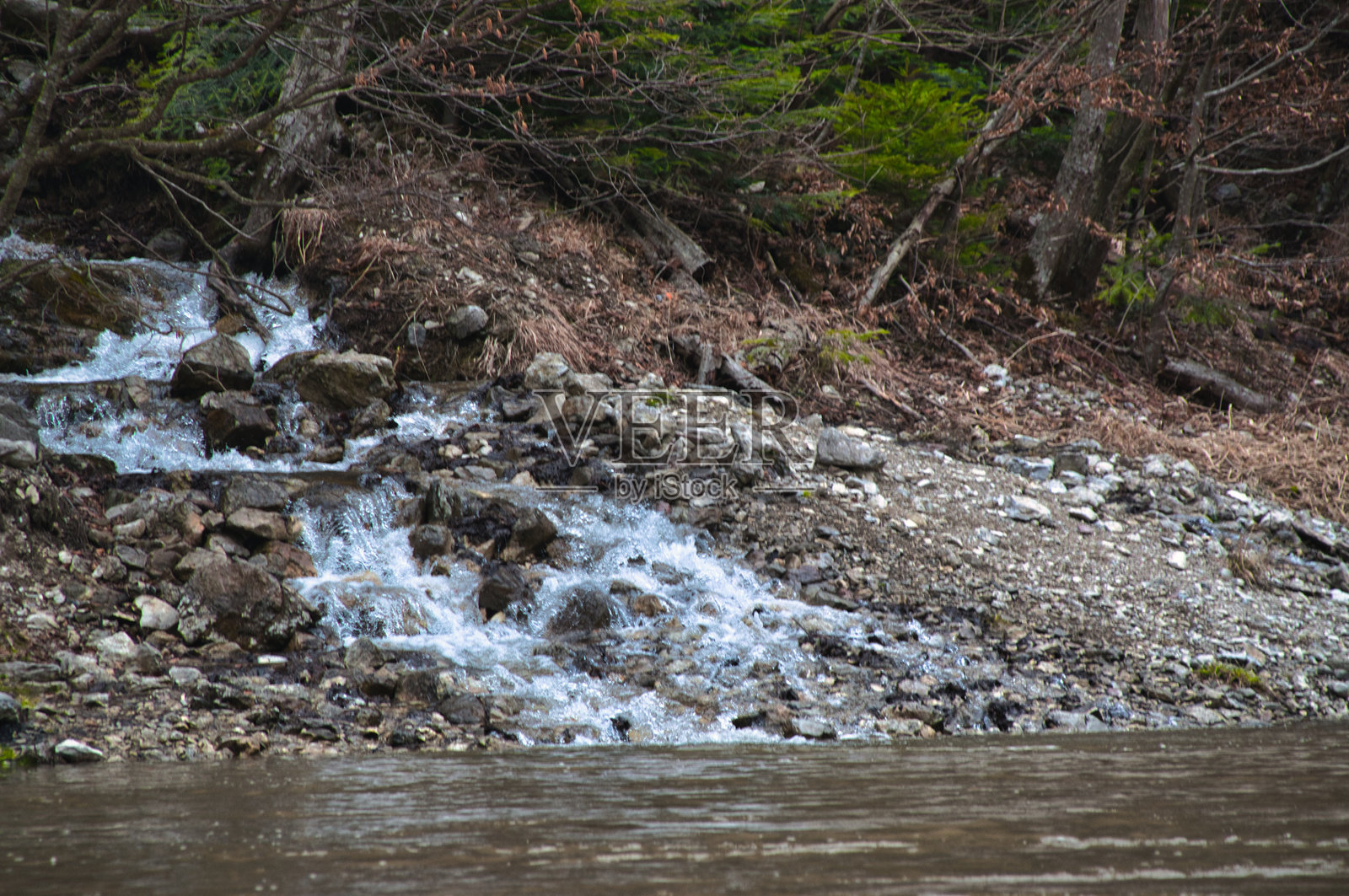 阴天时岩石河岸上的小瀑布照片摄影图片