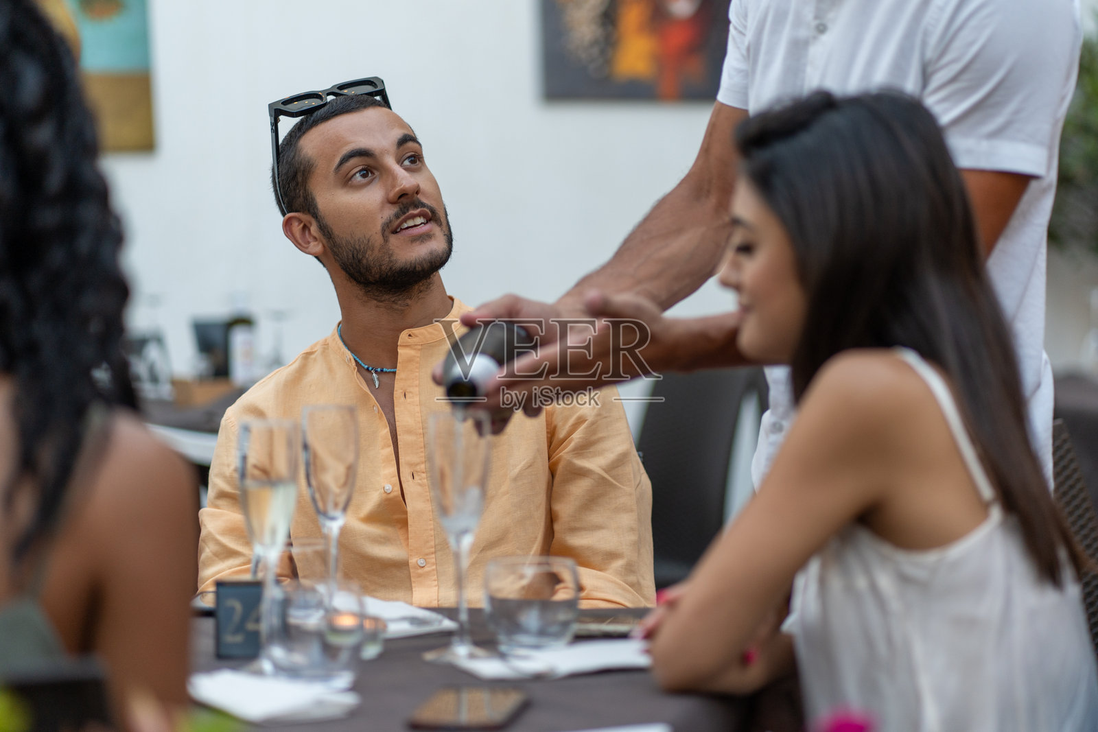 男子在户外晚餐时观察服务员倒酒照片摄影图片