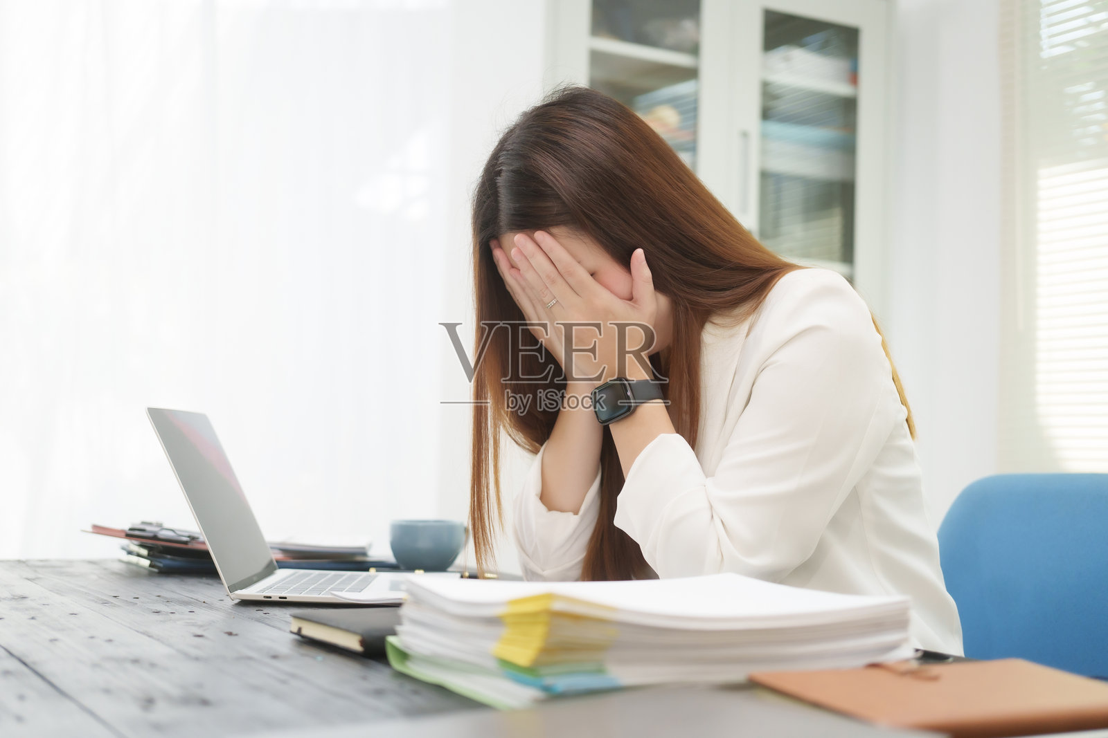 一位勤奋的女商人在她的办公桌前担任法律顾问,处理在线司法案件,同时忍受着办公室综合症的症状,如头痛、肌肉疼痛和脑力下降。照片摄影图片