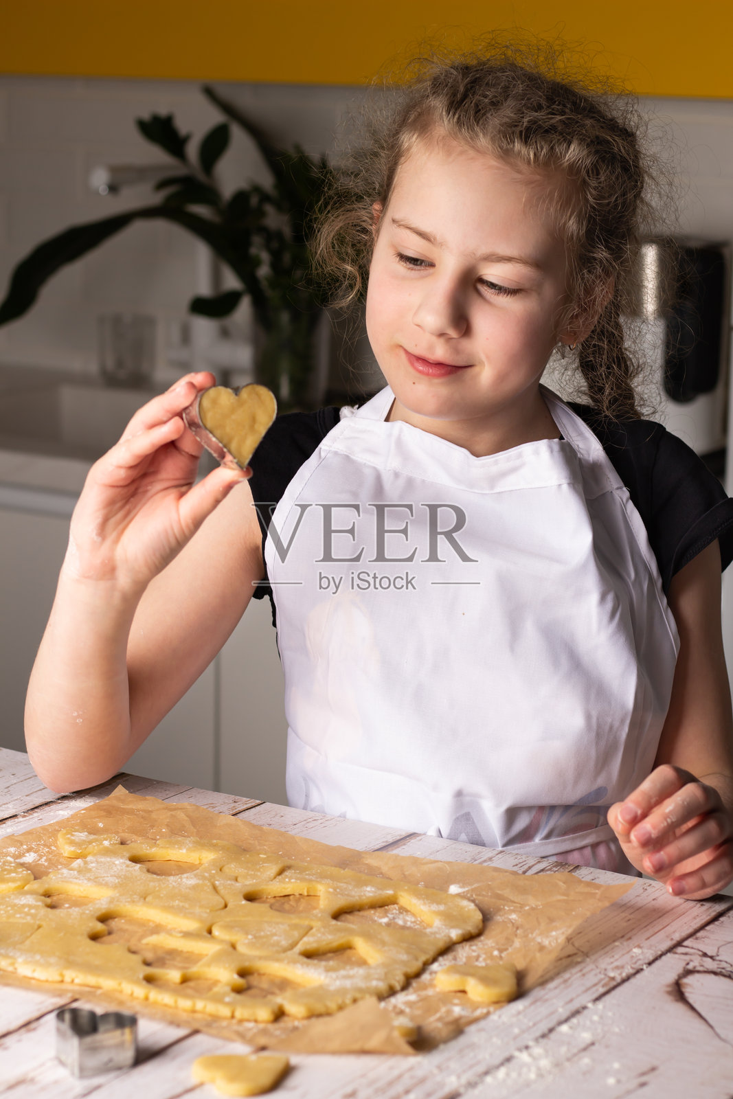 年轻女孩在明亮的厨房里烘焙心形饼干,正值下午时光照片摄影图片