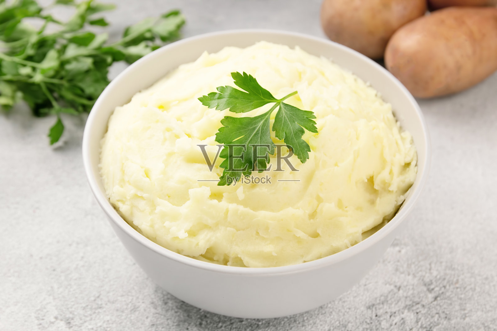 灰色混凝土背景上的白碗里装着土豆泥。健康食品照片摄影图片
