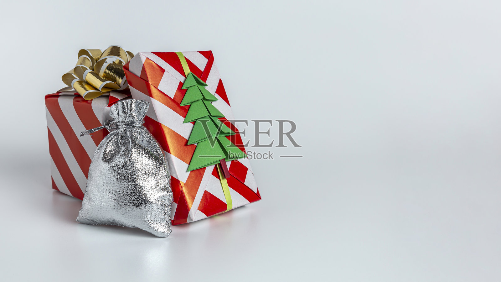 用金色蝴蝶结装饰的礼物和一棵绿色圣诞树照片摄影图片