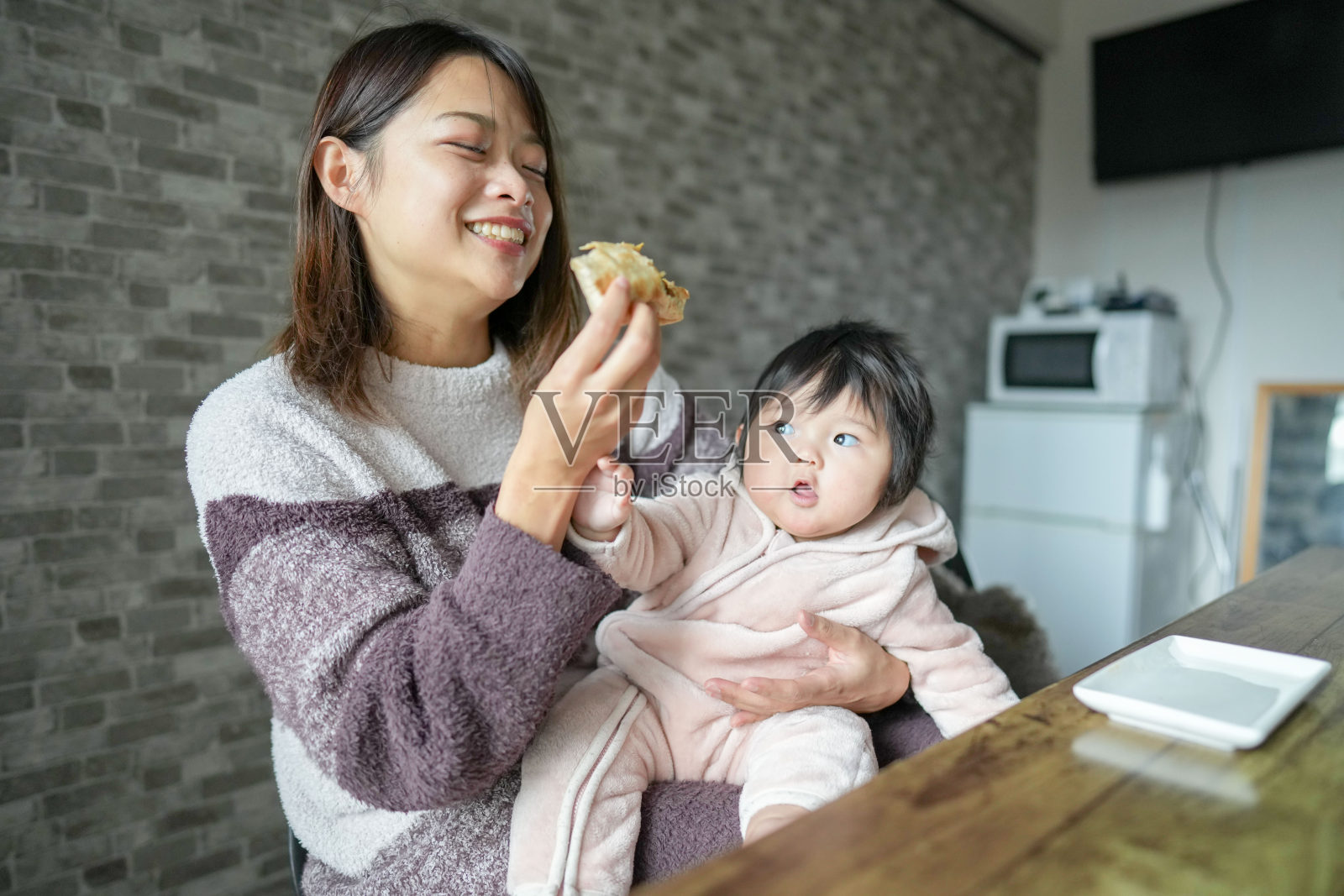 一位20多岁的日本母亲和她6个月大的女婴在房间里,正在吃墨西哥卷饼。照片摄影图片