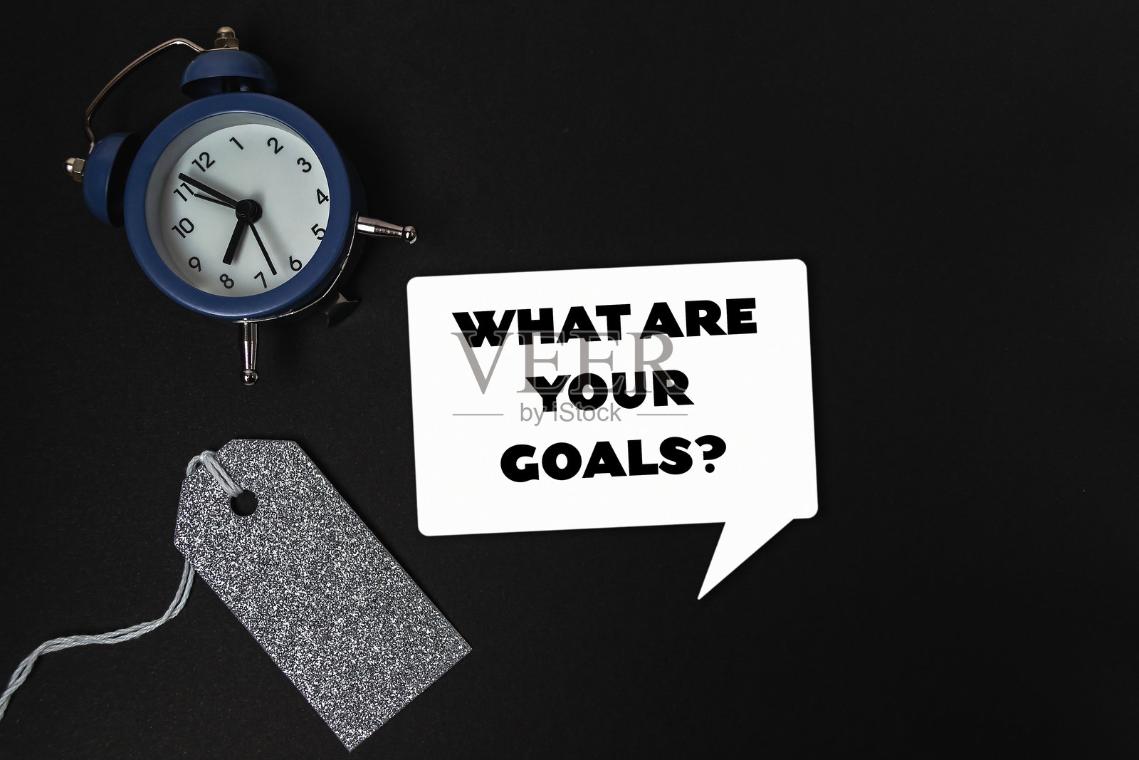 桌子上的时钟旁边有一个标签,上面写着“你的目标是什么”照片摄影图片